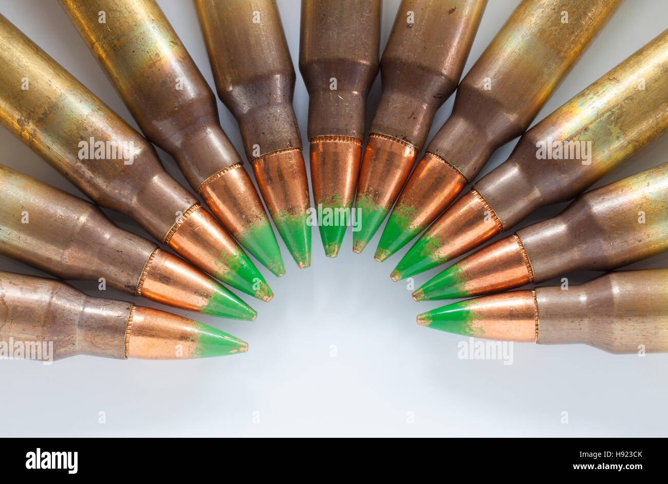 Rifle cartridges with green tipped bullets on white in a semi circle