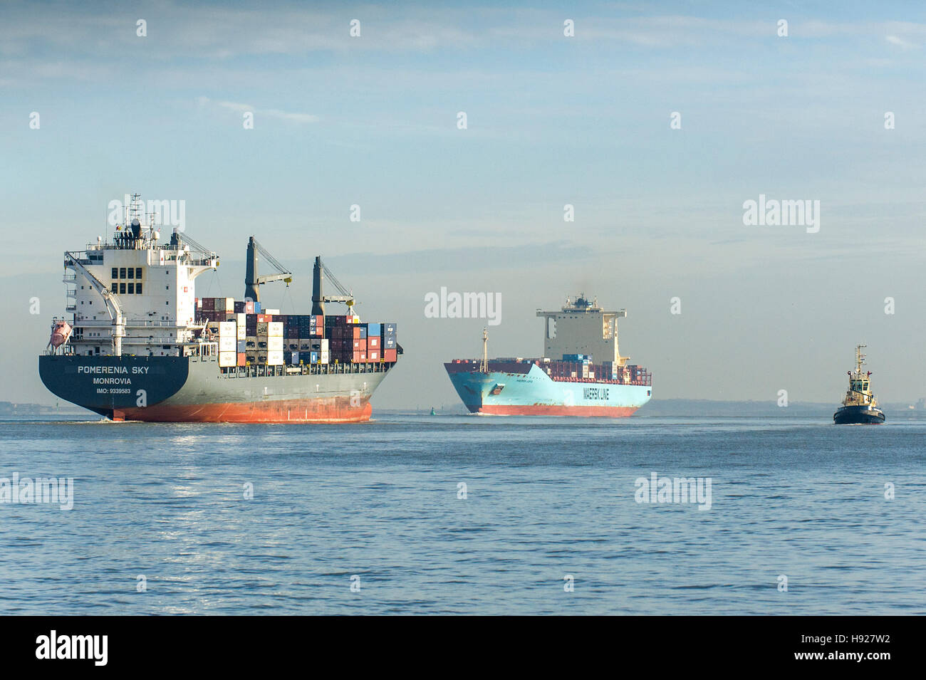 The container ship Pomerenia Sky steams downriver as the General Cargo Ship Maersk Lotus steams upriver on the River Thames. Stock Photo