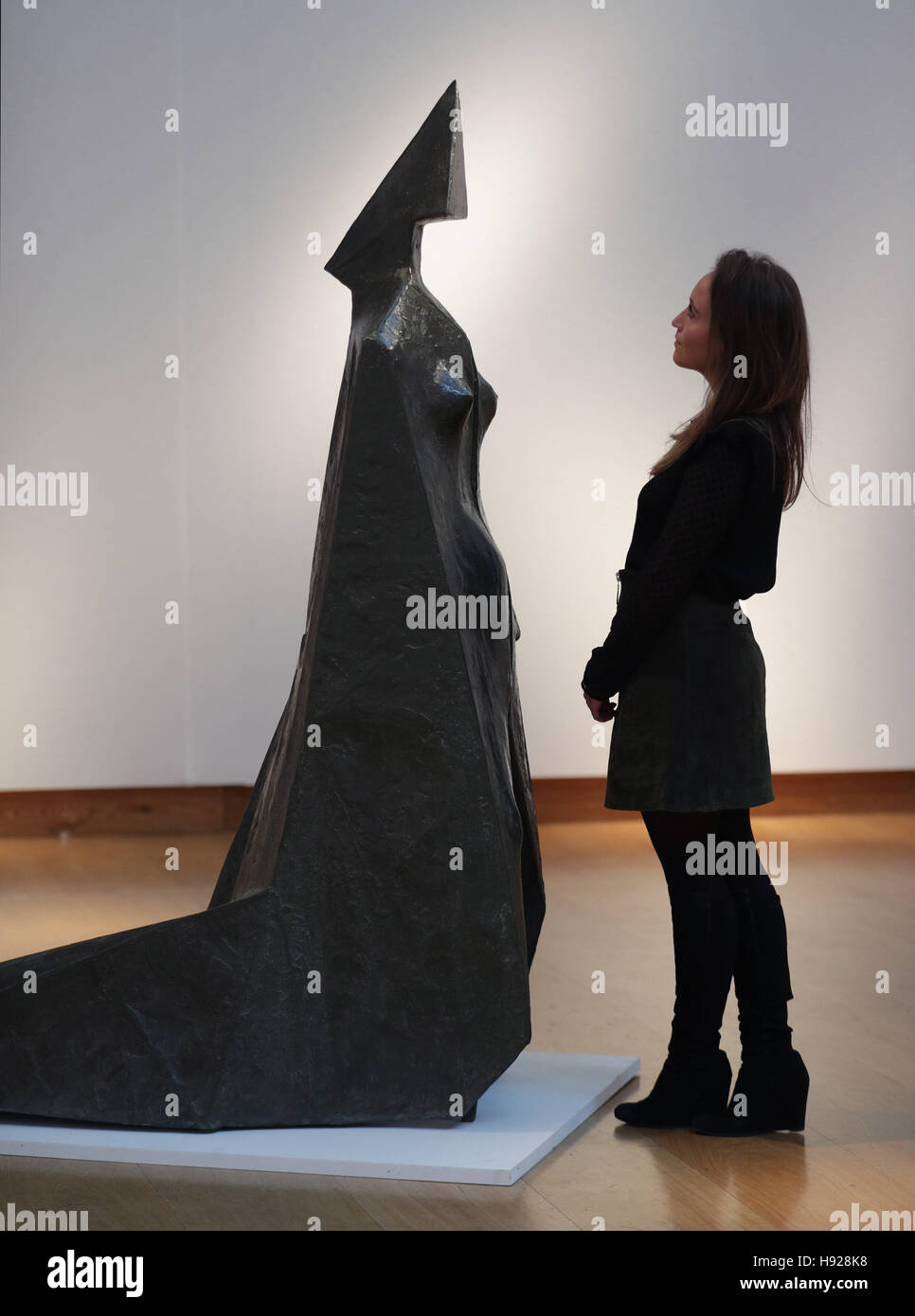 A member of staff looking at Lynn Chadwick's Cloaked Figure IX during a photocall in London ahead of Christie's Modern British &amp; Irish Art Evening Sale later this month. Stock Photo