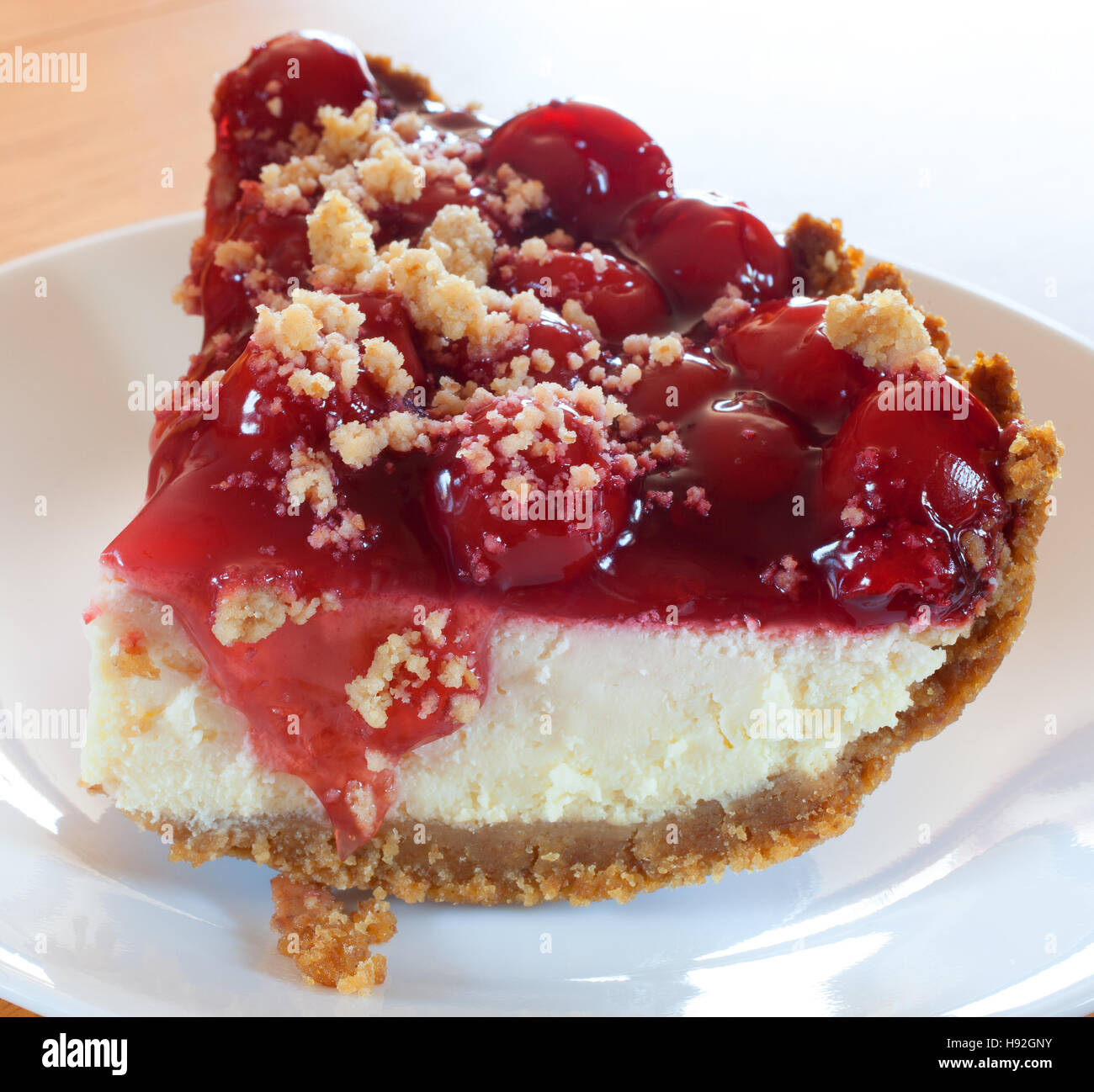 Thick piece of cheesecake with cherries and graham cracker crust Stock