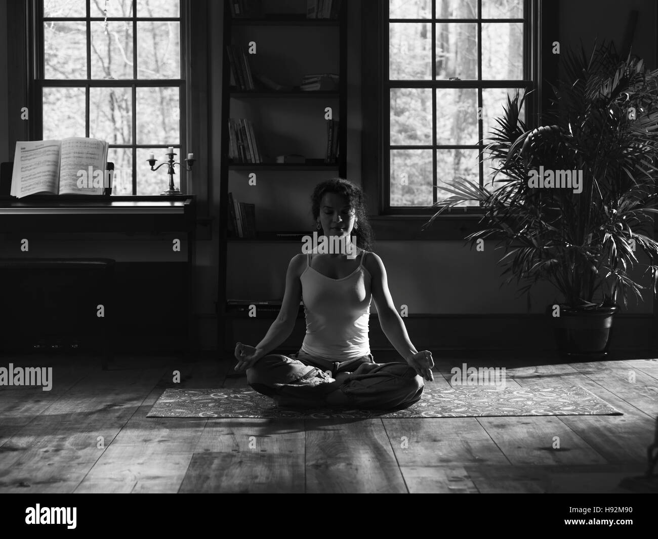 Woman meditating at home on a yoga mat artistic black and white portrait Stock Photo