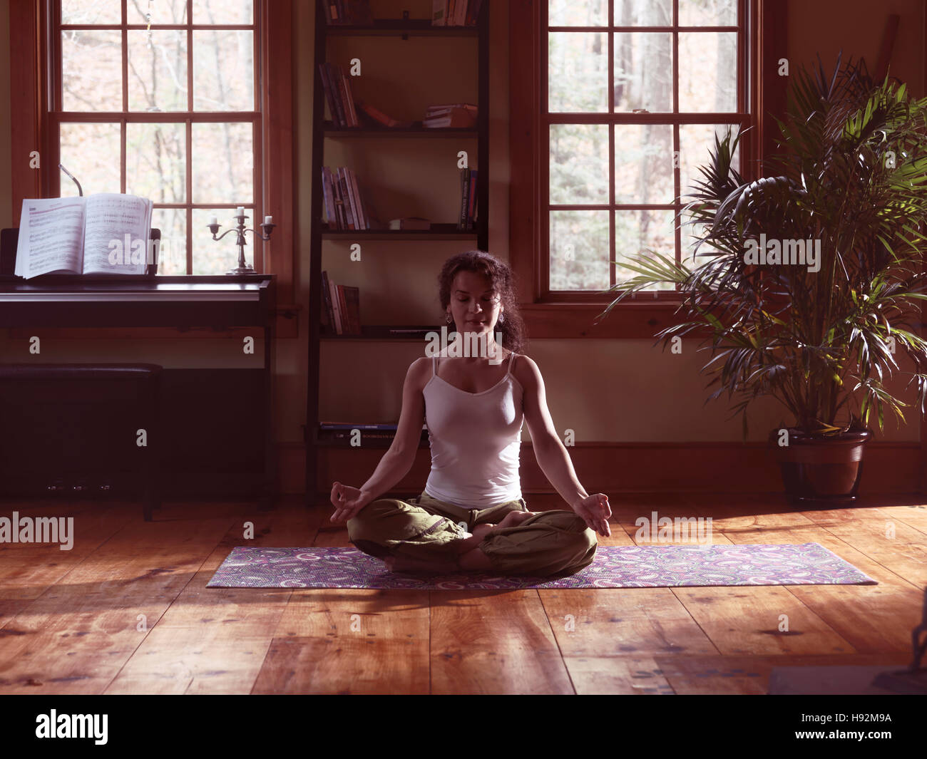 Woman meditating at home on a yoga mat artistic portrait Stock Photo