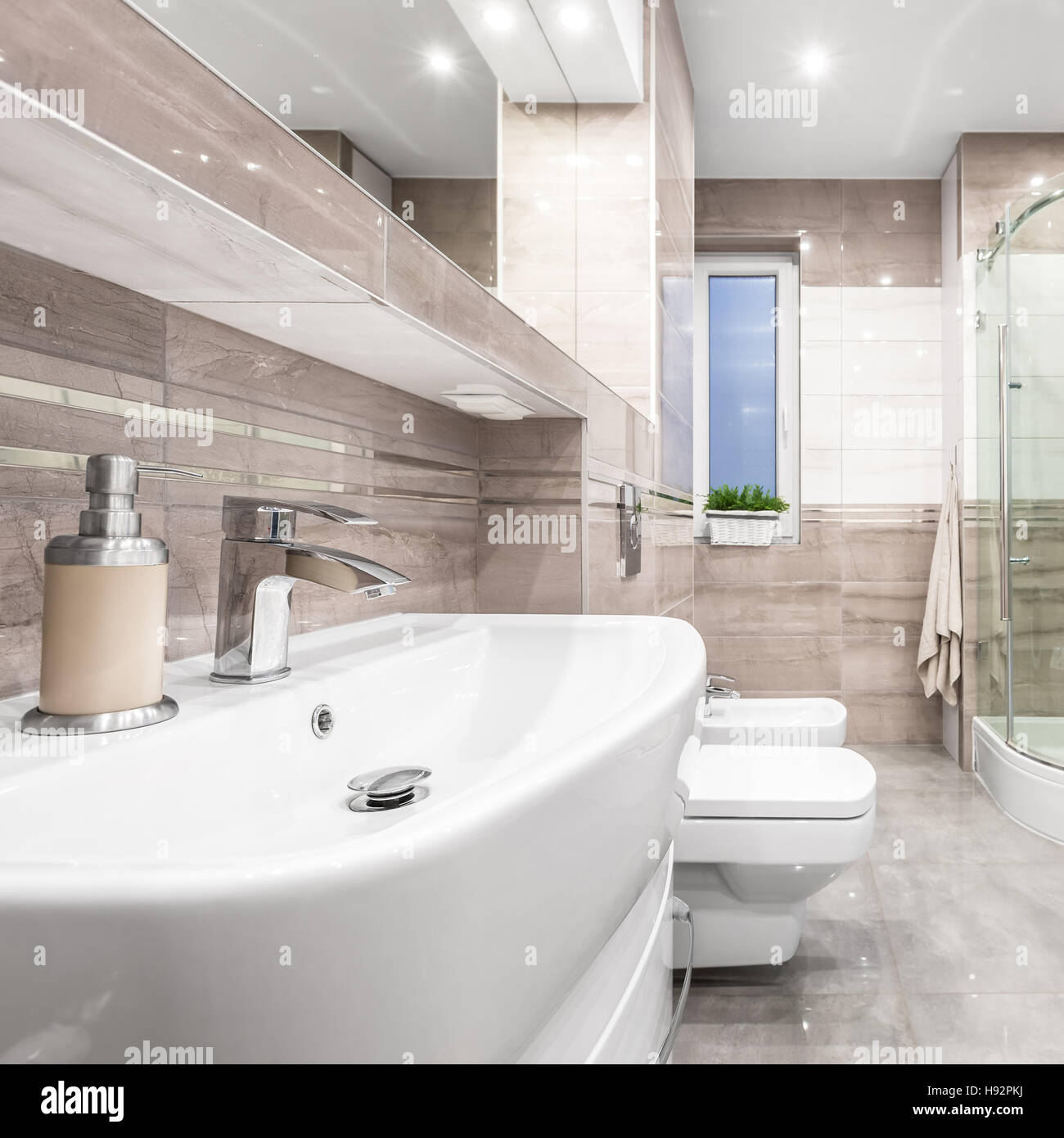Spacious high gloss bathroom in beige with basin, mirror, toilet, bidet
