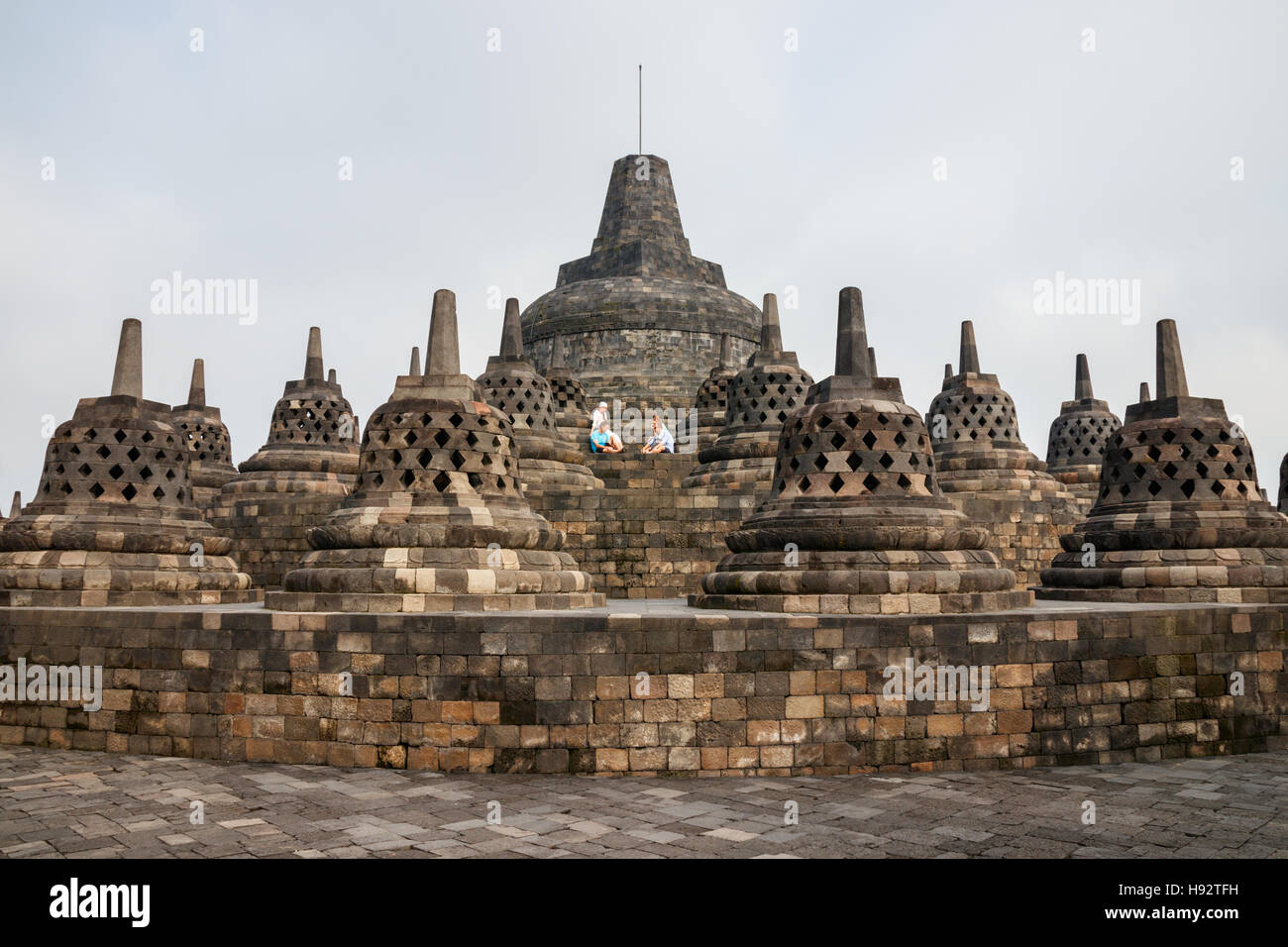 Unidentified tourists take a rest a the top level of the Borobudur temple complex. Java, Indonesia. Stock Photo