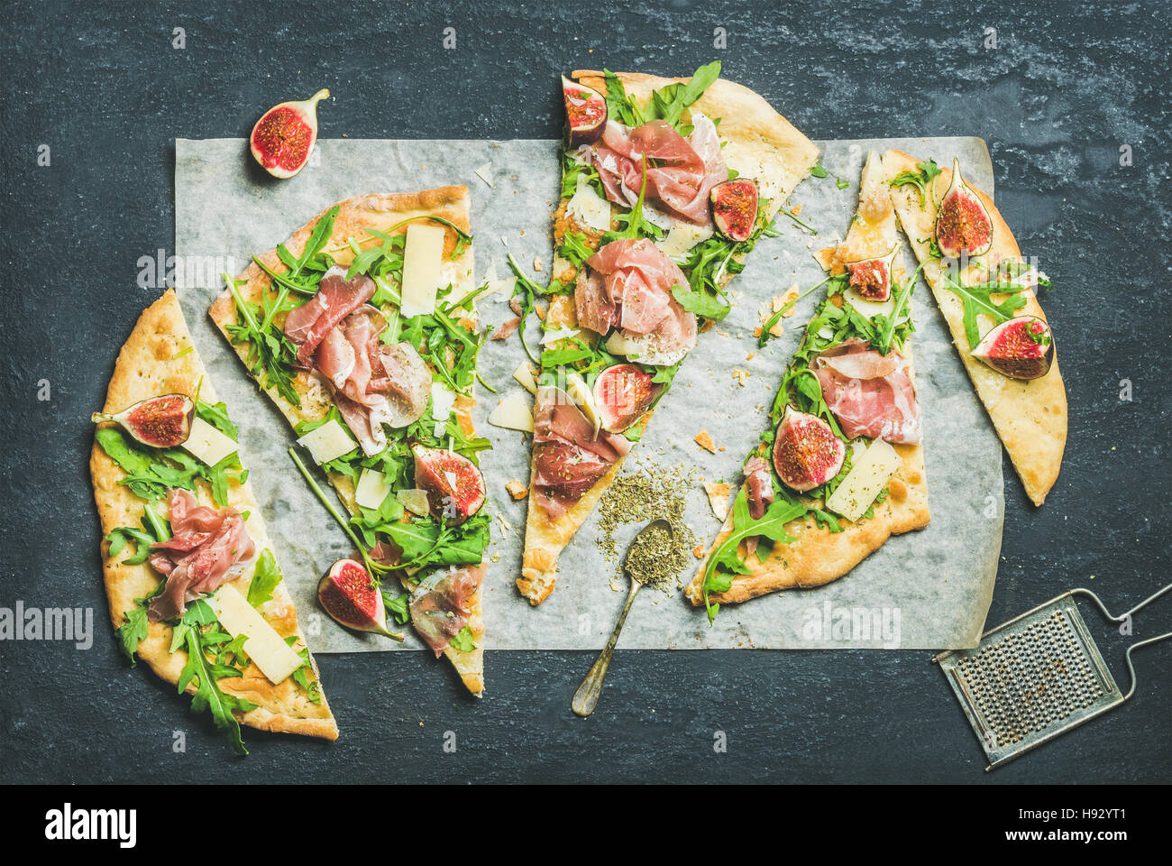 Fig, prosciutto, arugula and sage flatbread pizza on dark background