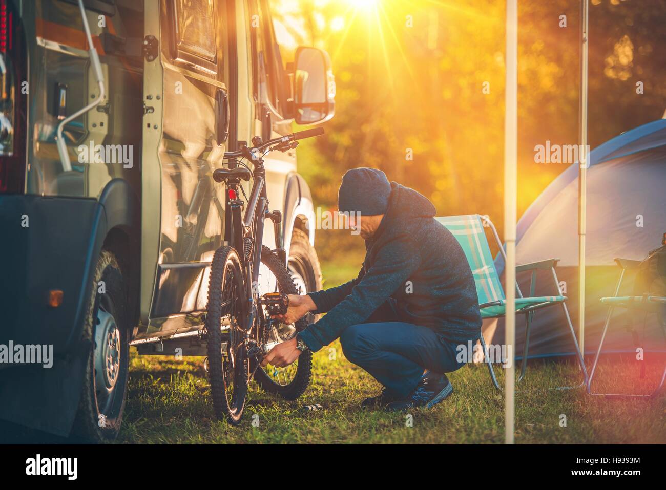 Fall Camping Time. Motorhome and Tent Camping. Men Preparing His Mountain Bike For a Trip. Stock Photo