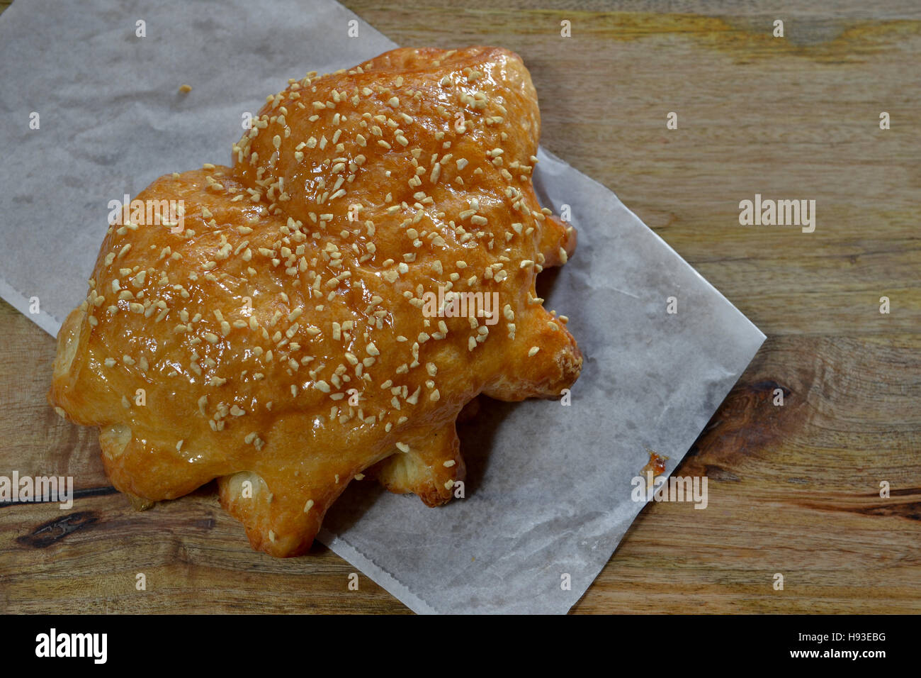 Austrian pastry filled with seasonal fruit, covered with almond crumbs and coated with sugar, on white paper over wooden background, viewed from above Stock Photo