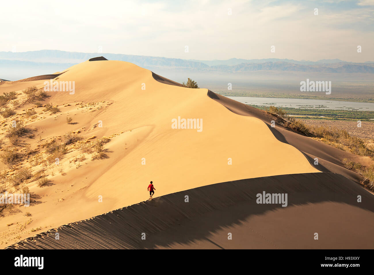 Man walking on beautiful sand dunes at sunrise. Altyn-Emel semi-desert, Kazakhstan. Stock Photo