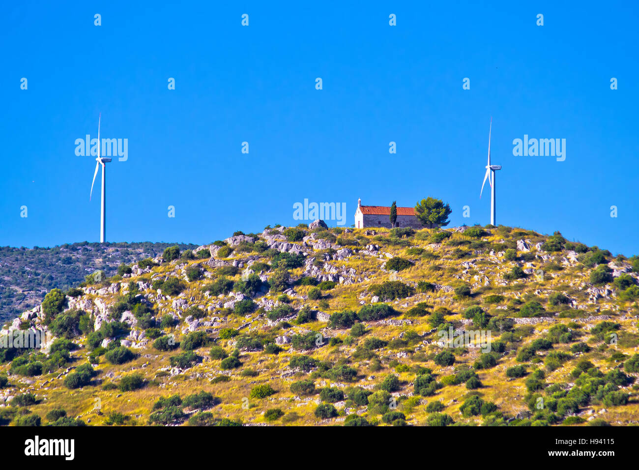 Old stone church and green energy plant on hill in Dalmatia, Croatia Stock Photo