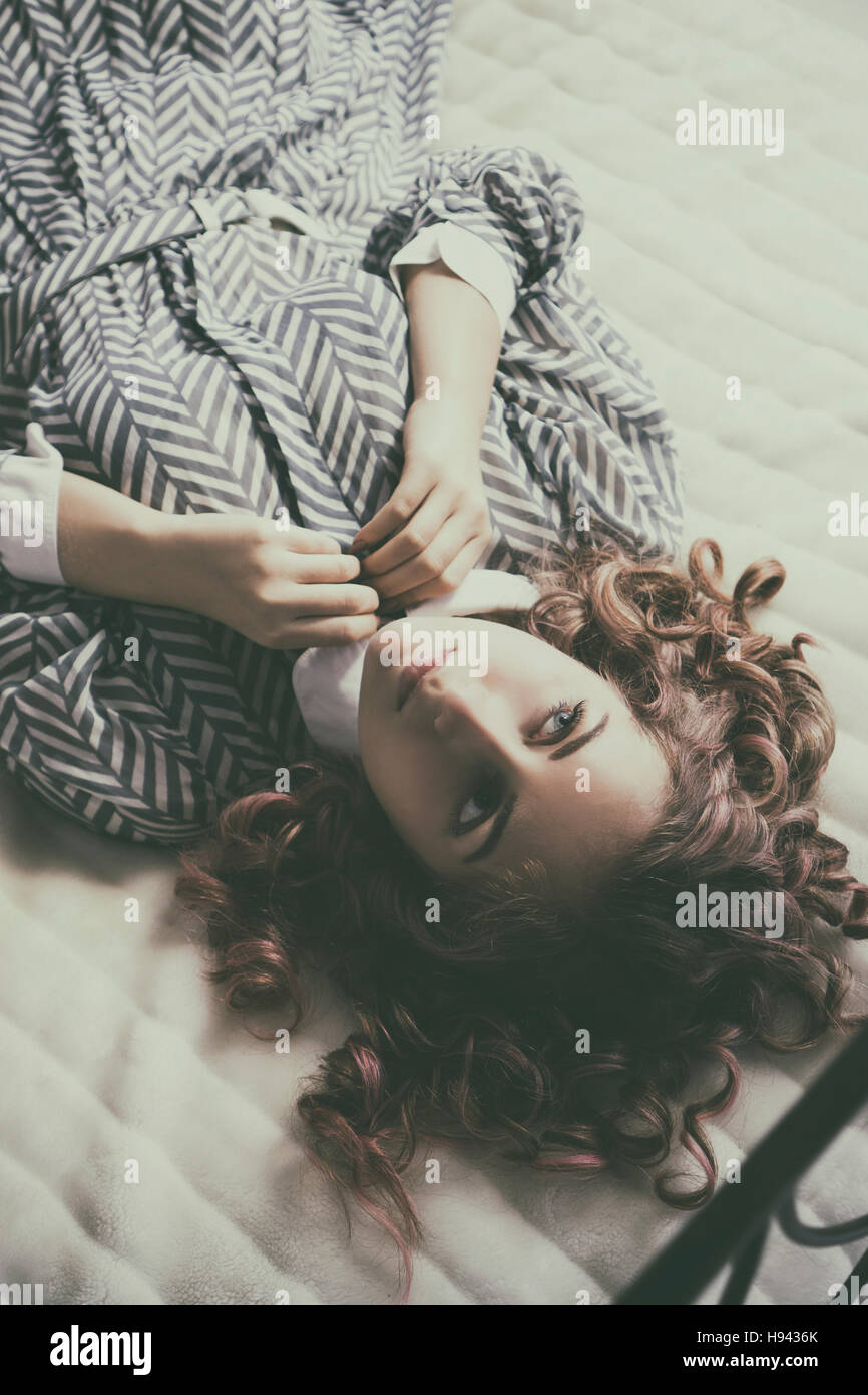 Pensive woman laying down in bed looking away Stock Photo