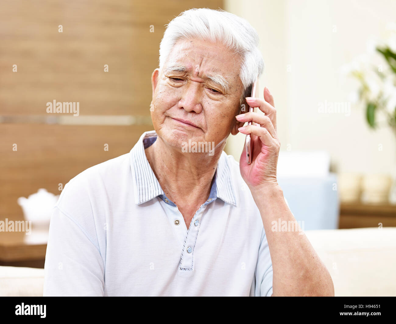 senior asian man talking using mobile phone, appears to be unhappy, sad or angry Stock Photo