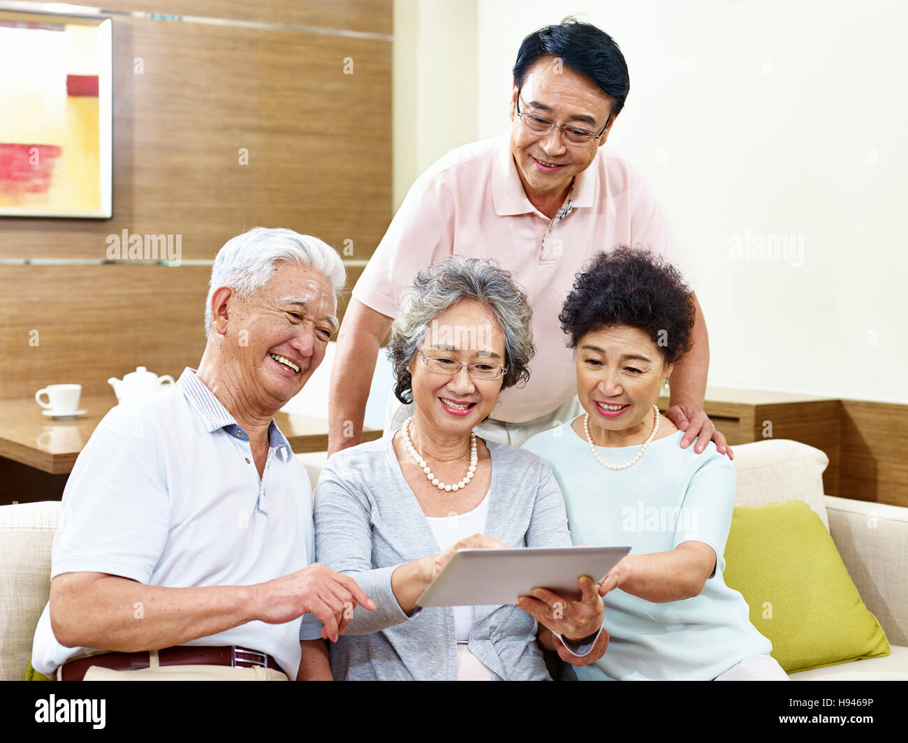 two active senior asian couples looking at tablet computer, happy and smiling Stock Photo
