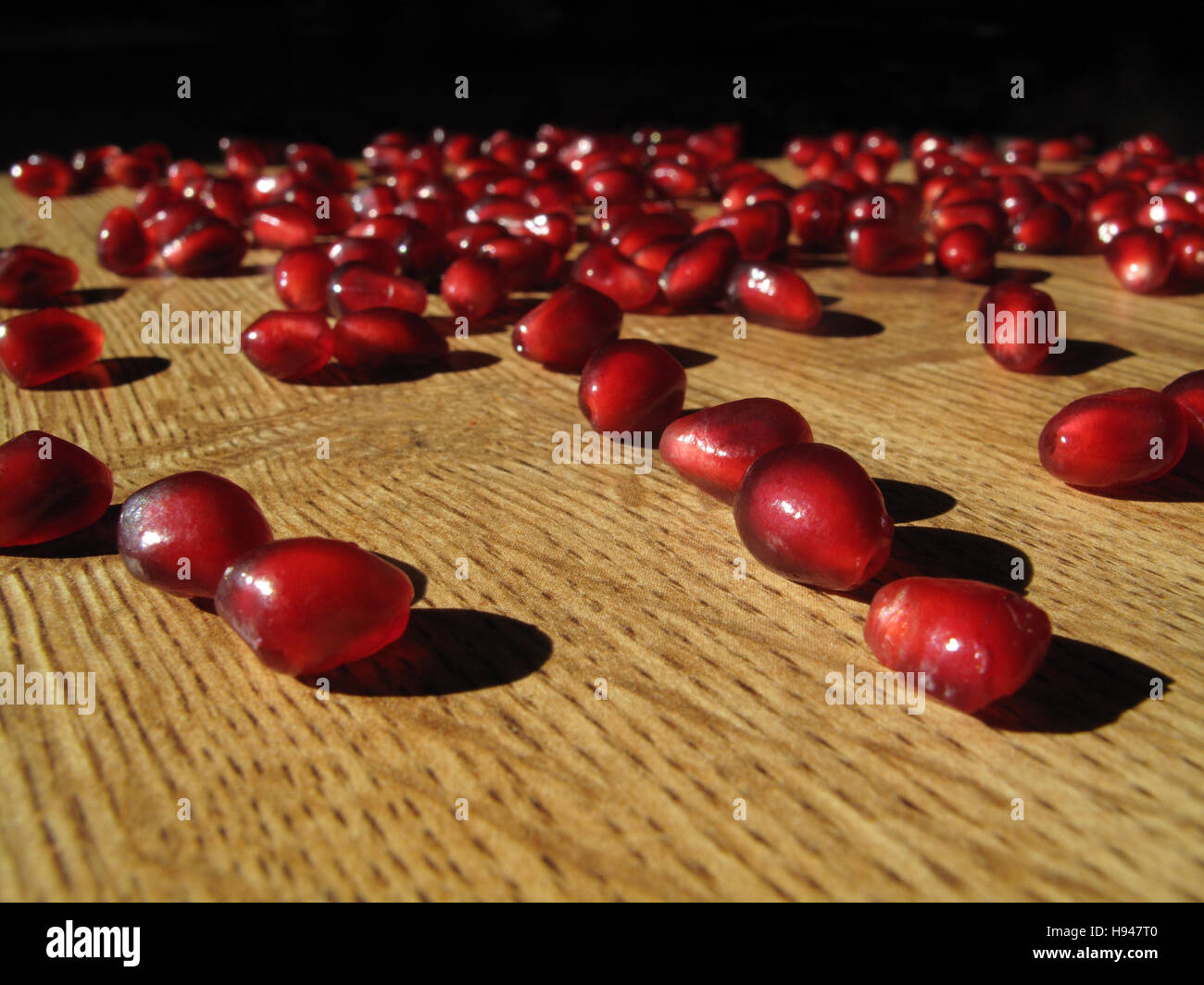 Pomegranate seeds on wood grained table Stock Photo