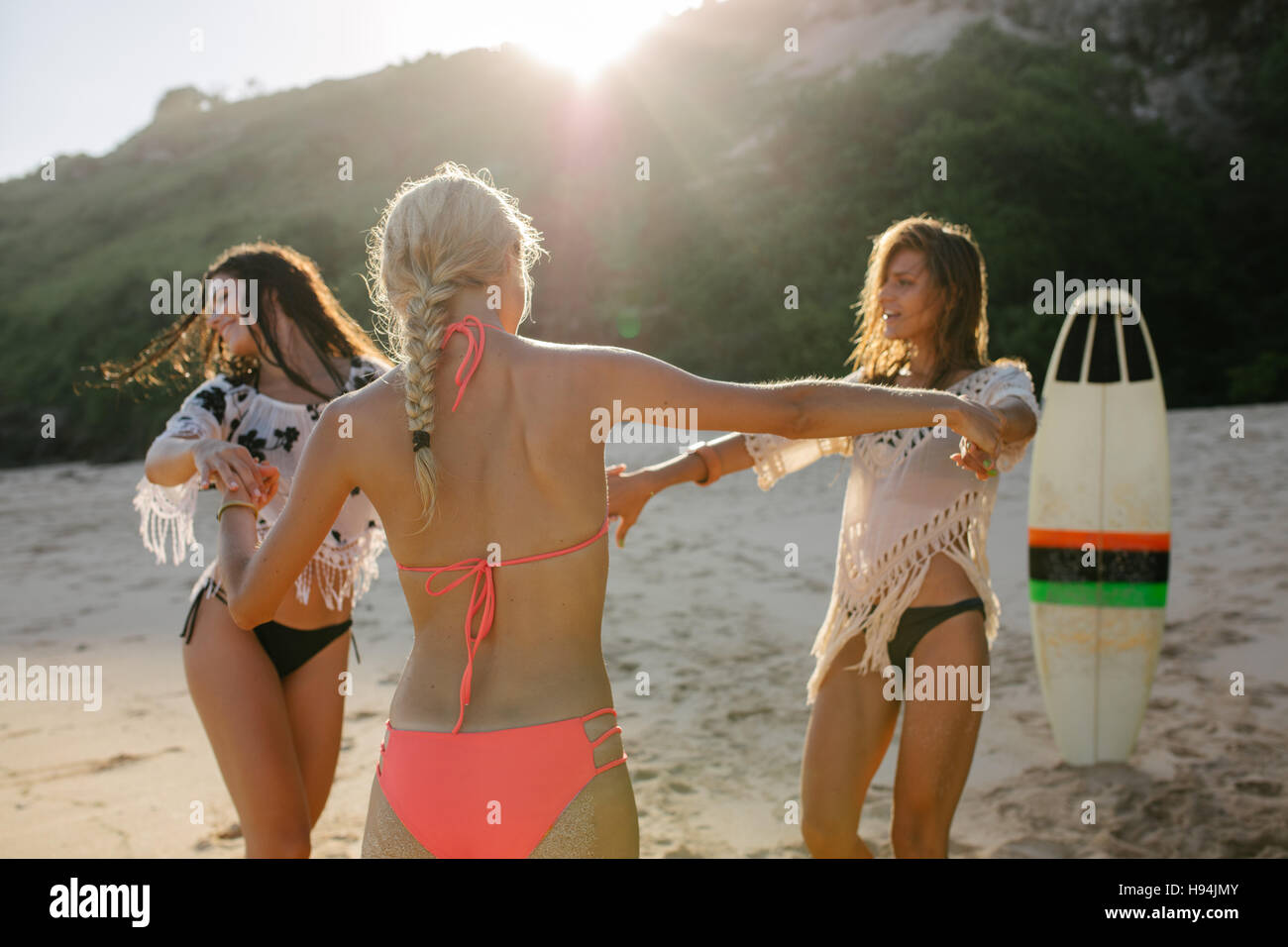 Happy female friends partying on the beach and dancing. Women having fun on the beach party. Stock Photo