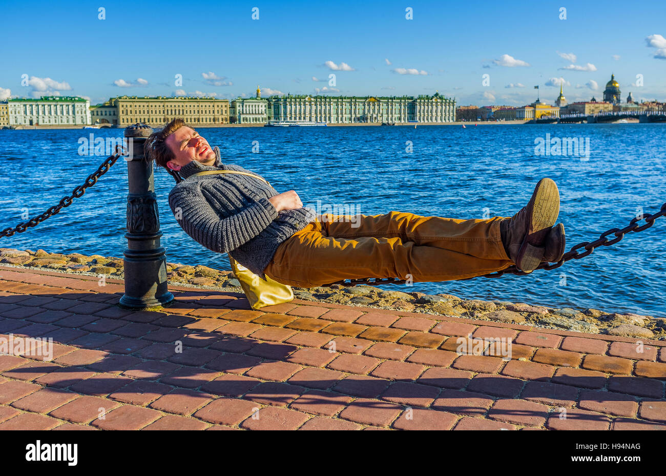 SAINT PETERSBURG - APRIL 24, 2015: The best way to take a sunbathe without a sunbed is to lie on chains on the embankment of the river, on April 24 in Stock Photo