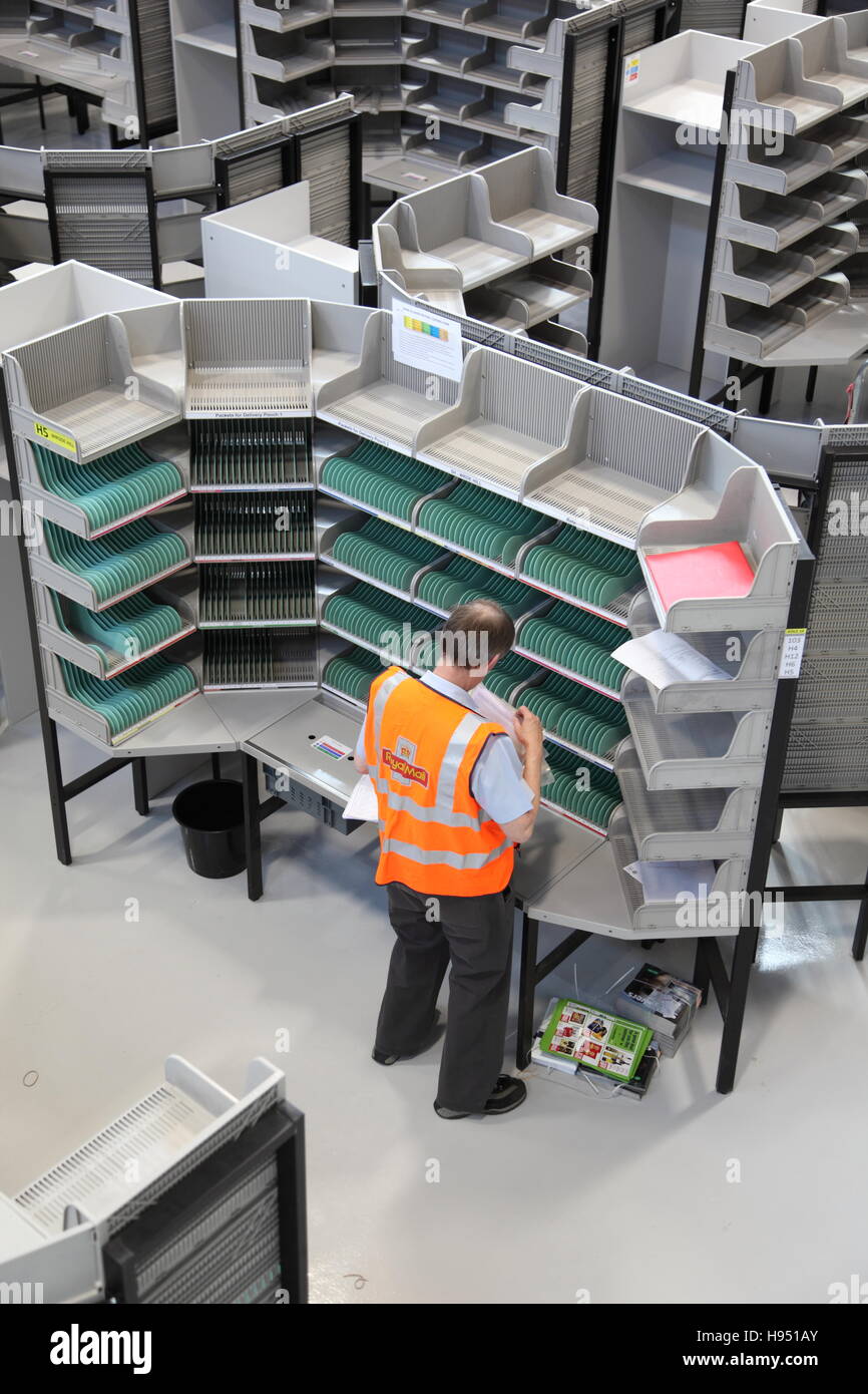 A single postman works at a sorting desk in a new Post Office sorting office in Southern England, UK Stock Photo