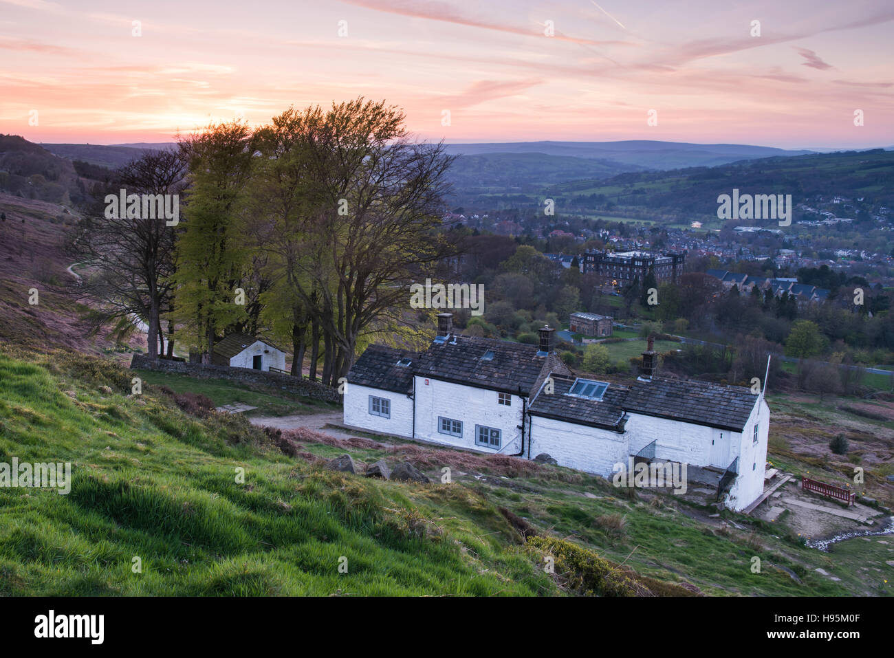 View at sunset from Ilkley Moor of White Wells Spa Cottage (foreground) with the town in the valley - West Yorkshire, England. Stock Photo