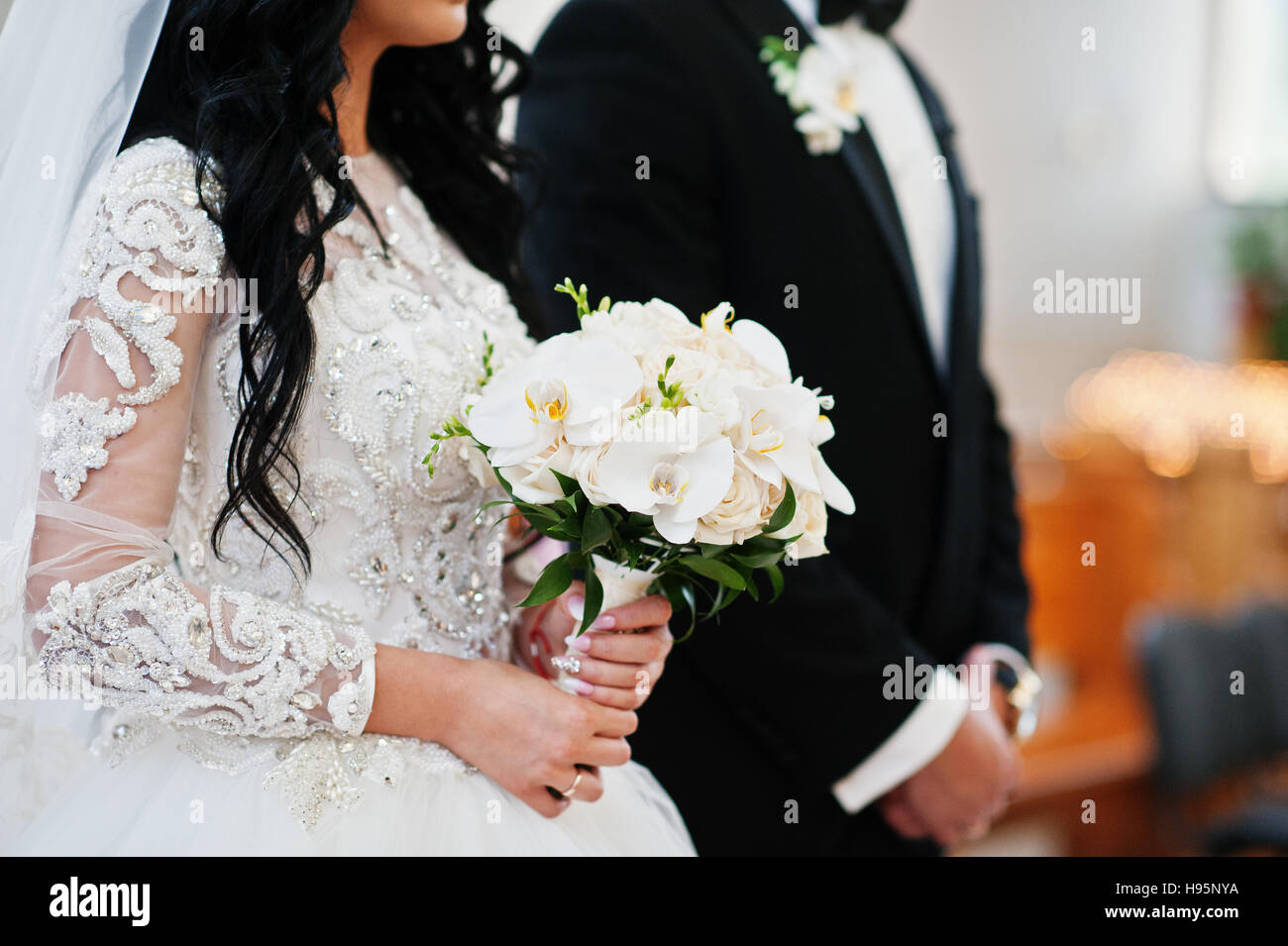Wedding Bouquet Of White Orchids On Hand Of Bride On Church