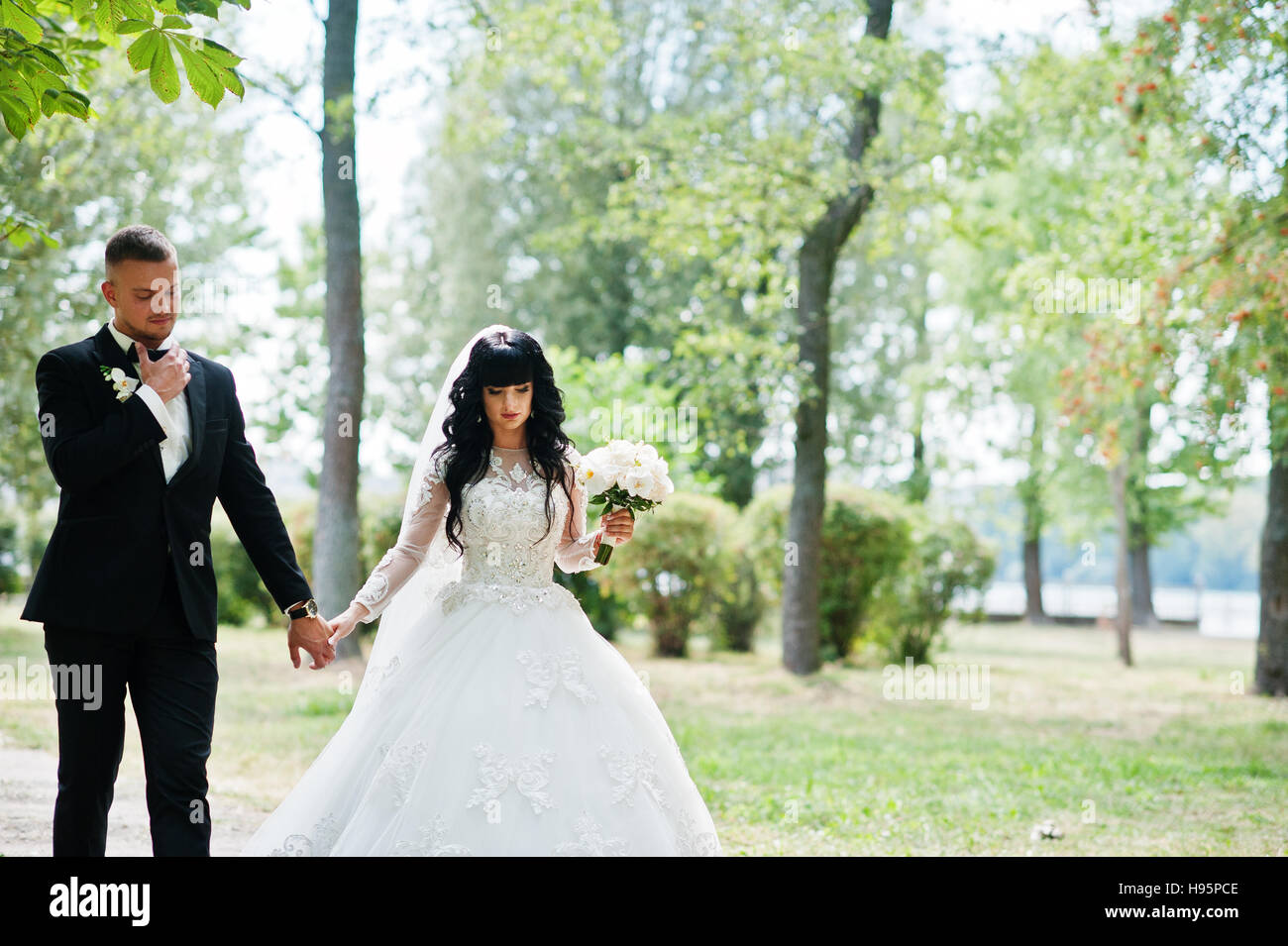 Great wedding couple walking on park holding hands. Stock Photo
