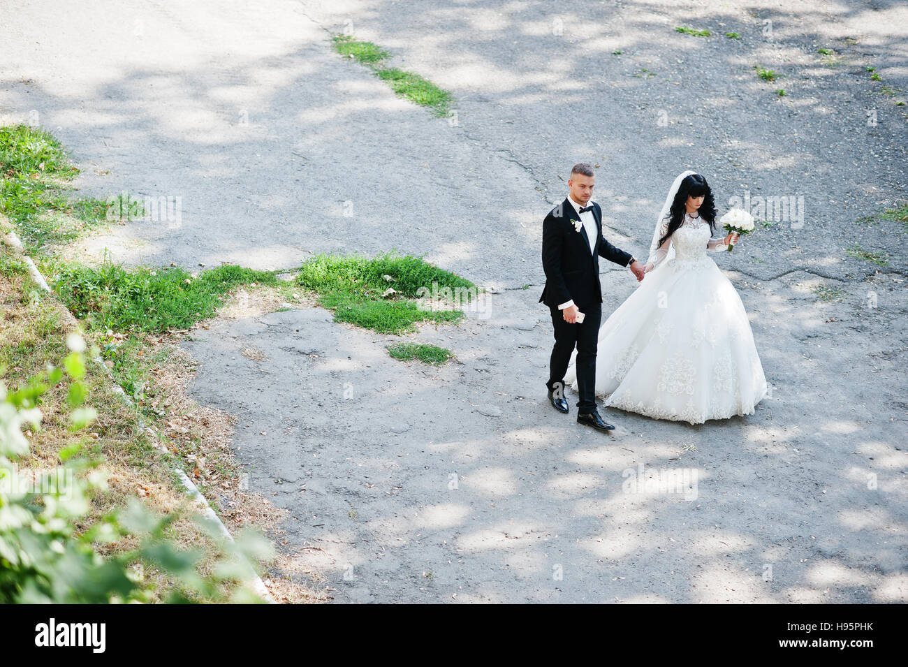 View from above of stylish wedding couple on road at park. Stock Photo