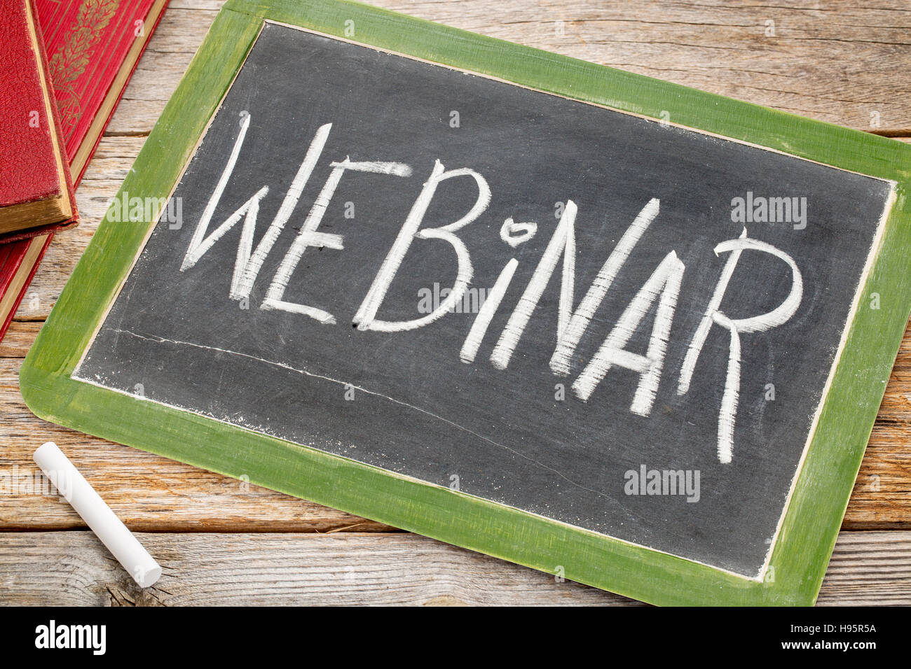 webinar word in white chalk handwriting on a vintage slate blackboard with books Stock Photo