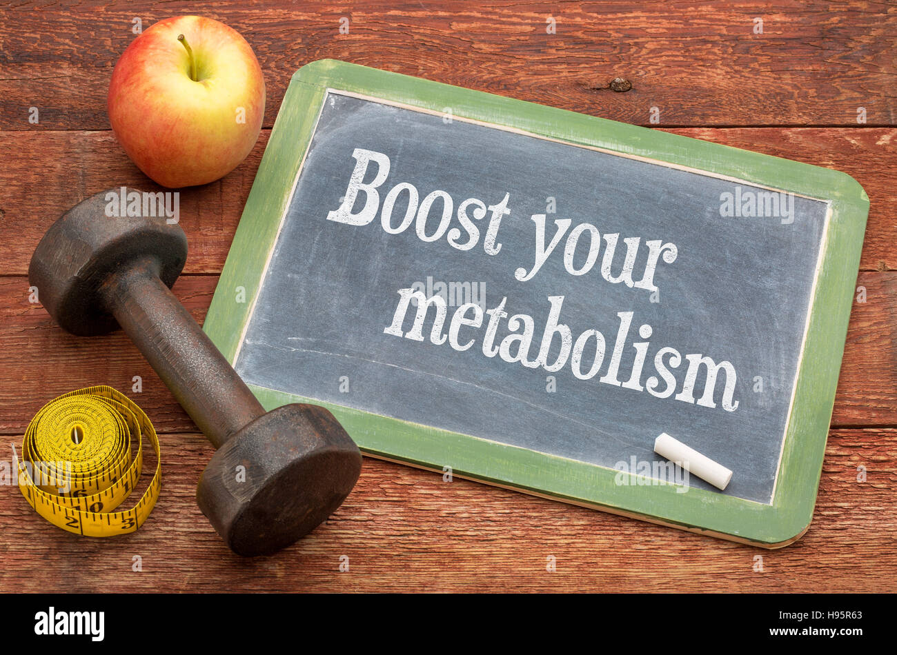 Boost your metabolism concept -  slate blackboard sign against weathered red painted barn wood with a dumbbell, apple and tape measure Stock Photo