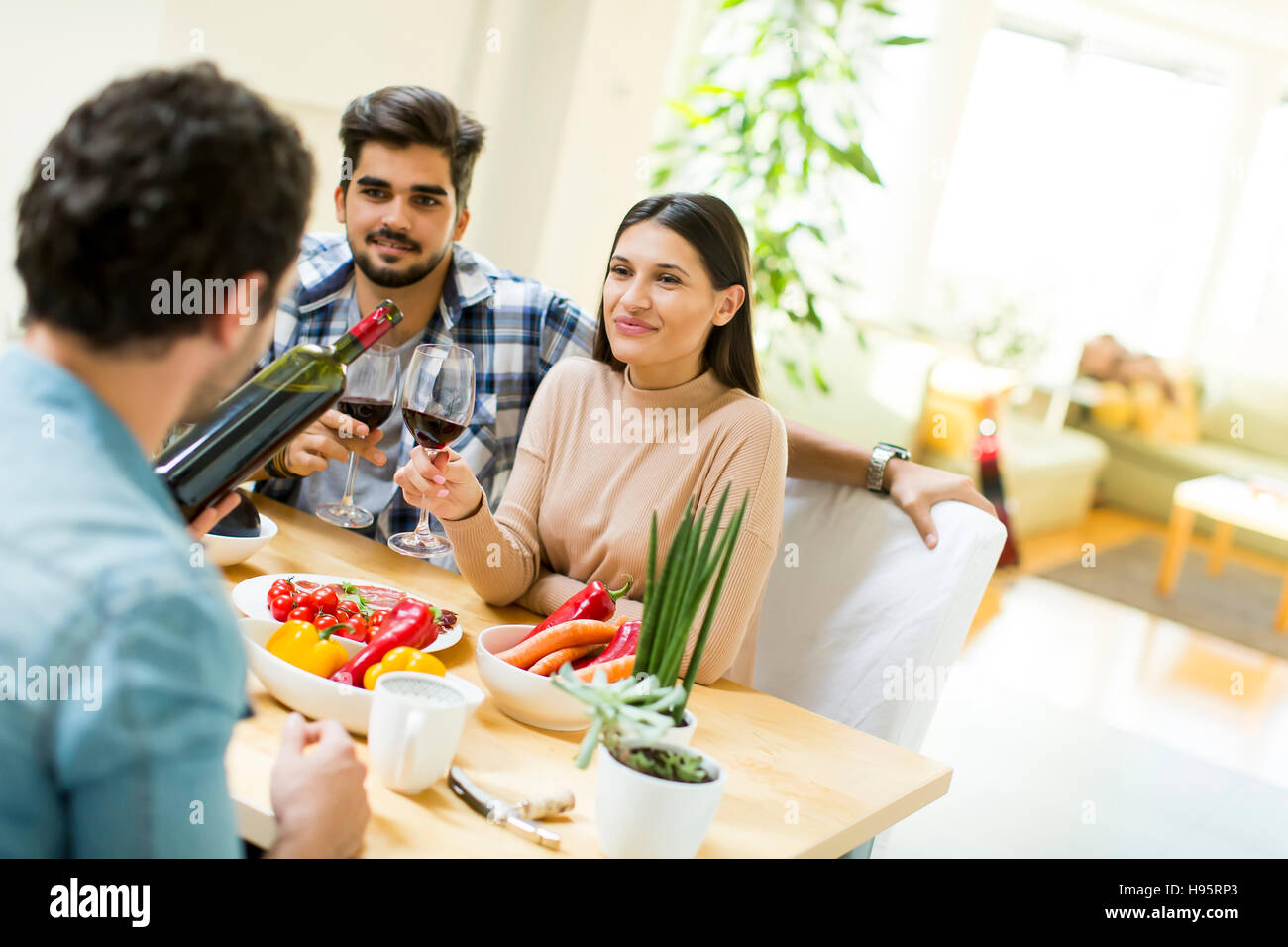 Group of happ young people sitting by the table eating and drinking red wine Stock Photo Alamy