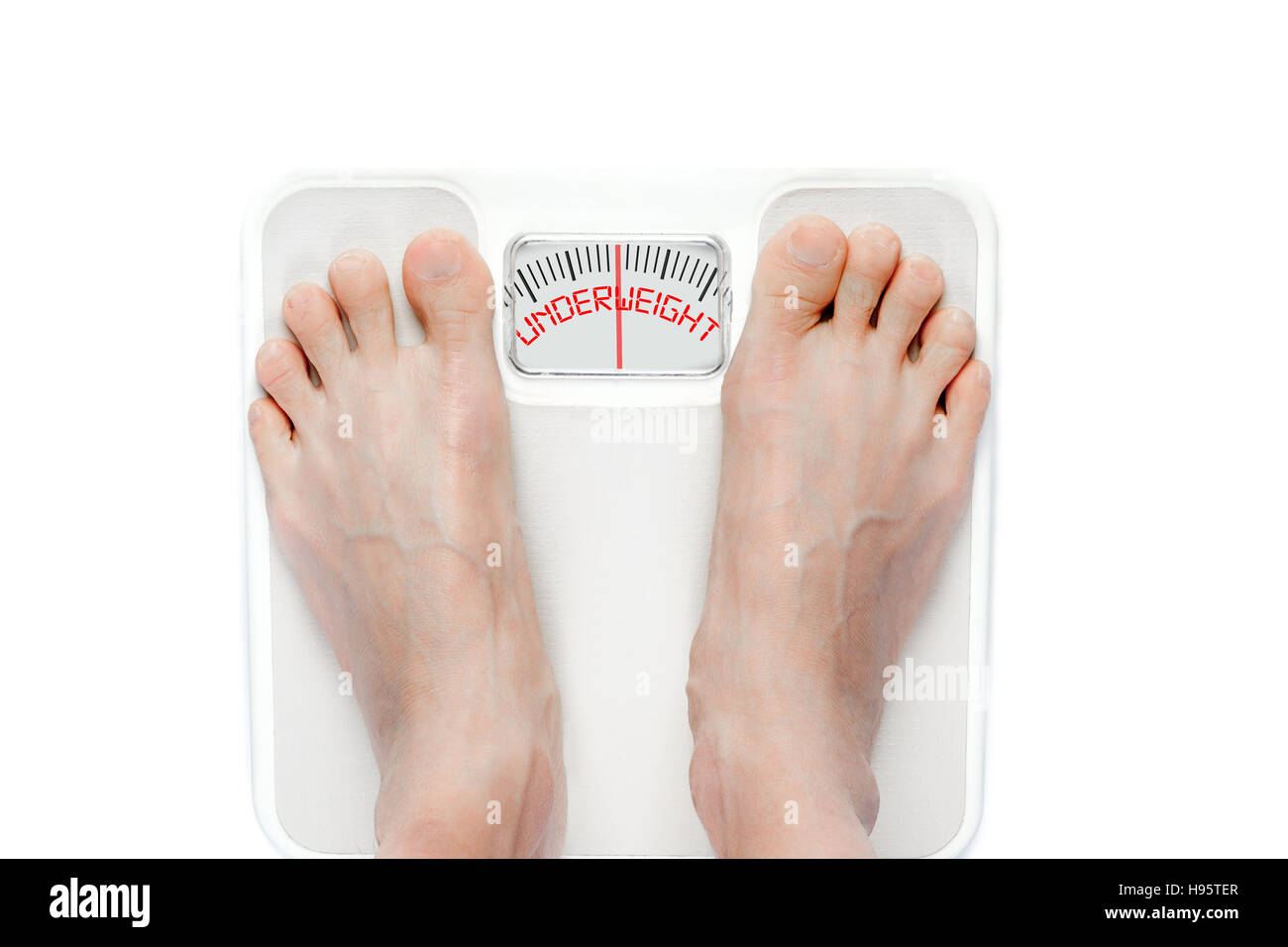 Feet on mechanical bathroom scale with the word UNDERWEIGHT on screen. Signifies eating disorder problems requiring proper treatment. Stock Photo