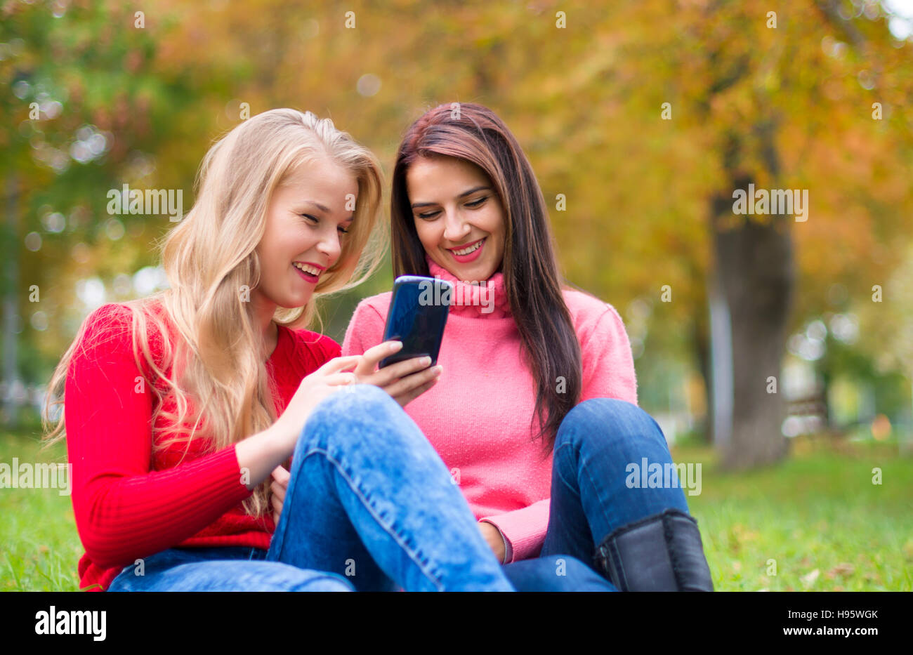 Two girls in park with a mobile phone Stock Photo