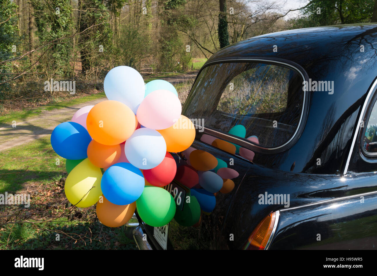 multi colored balloons on the back of a black vintage car Stock Photo