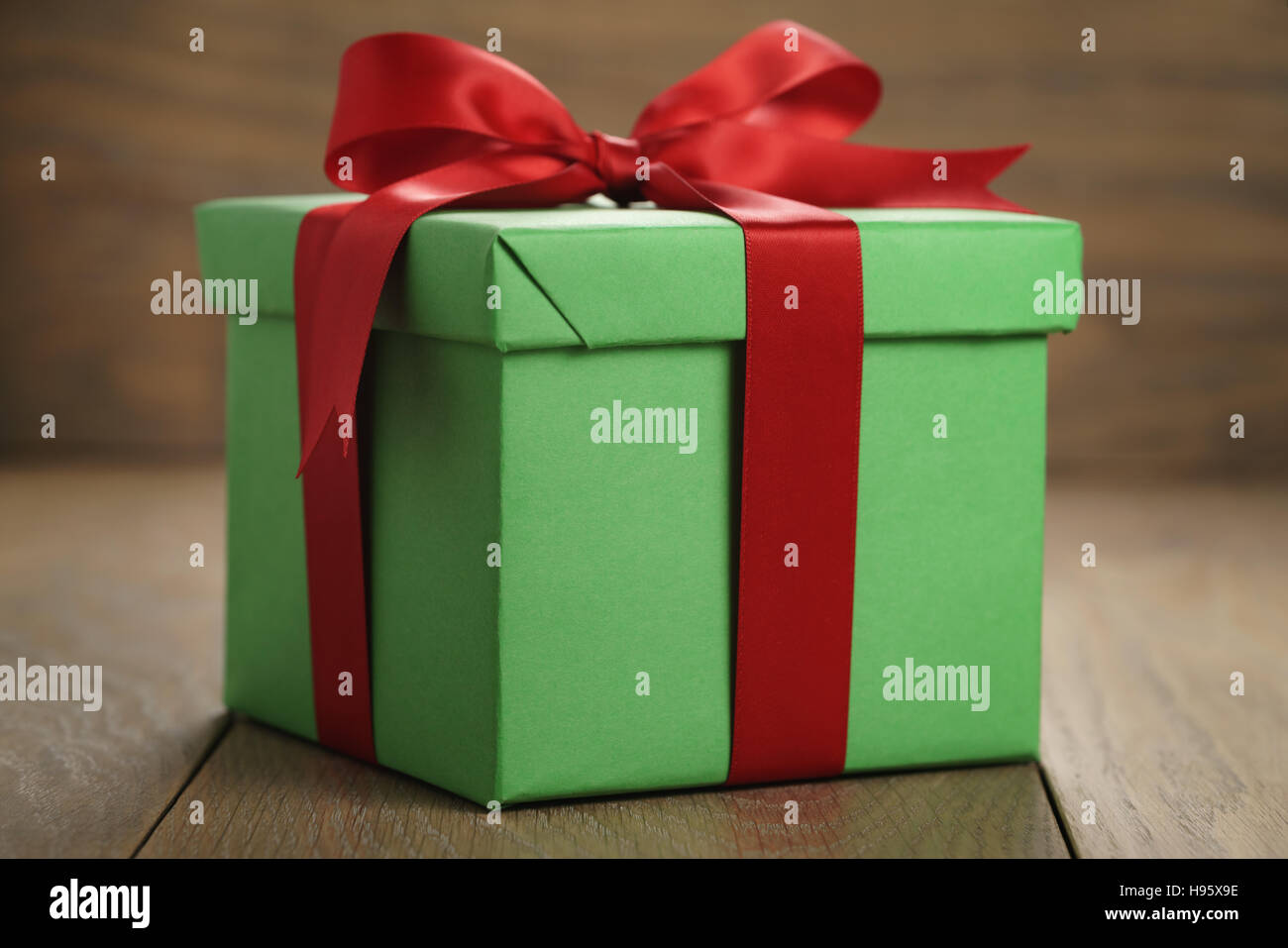 green paper gift box gift box with lid and red ribbon bow on wood table