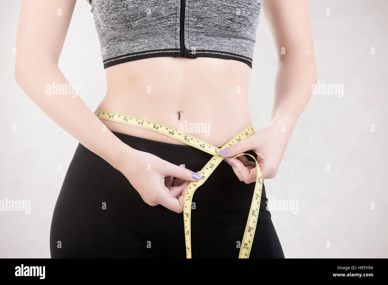 Woman measuring her waist with a yellow measuring tape, isolated Stock Photo