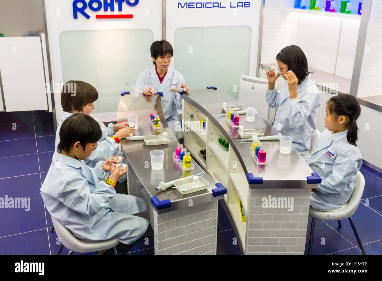 Japan, Nishinomiya, KidZania, children activity play park. Children in white coats sitting listening to lecturer in Rohto Medical lab Stock Photo