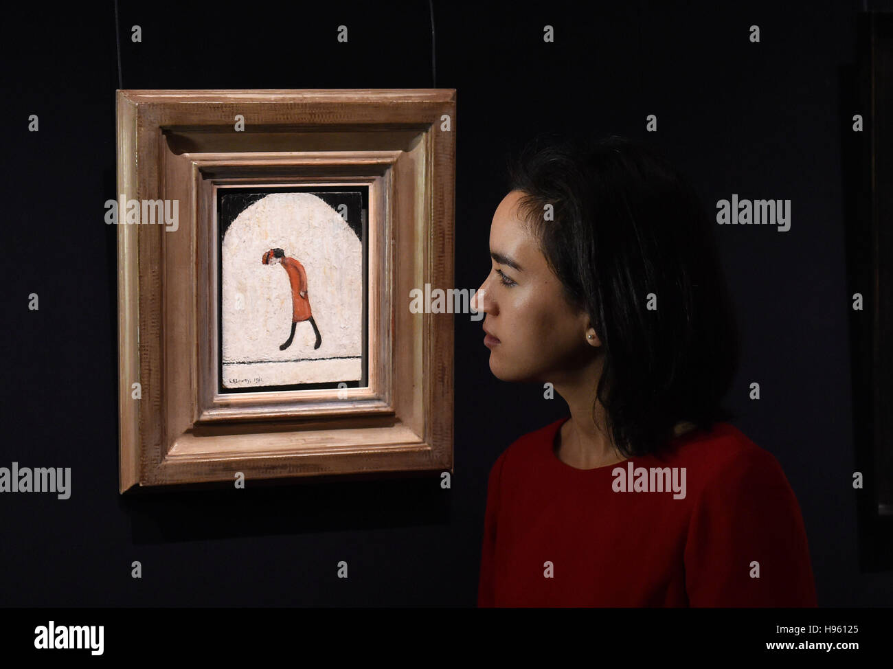 Staff at Sotheby's, London, stand next to a painting titled Woman In Red, 1961, by Laurence Stephen Lowry in the Modern & Post-War British Art section and estimated at £60,000 - £80,000, which makes up part of Sotheby's forthcoming National Treasures auctions. Stock Photo