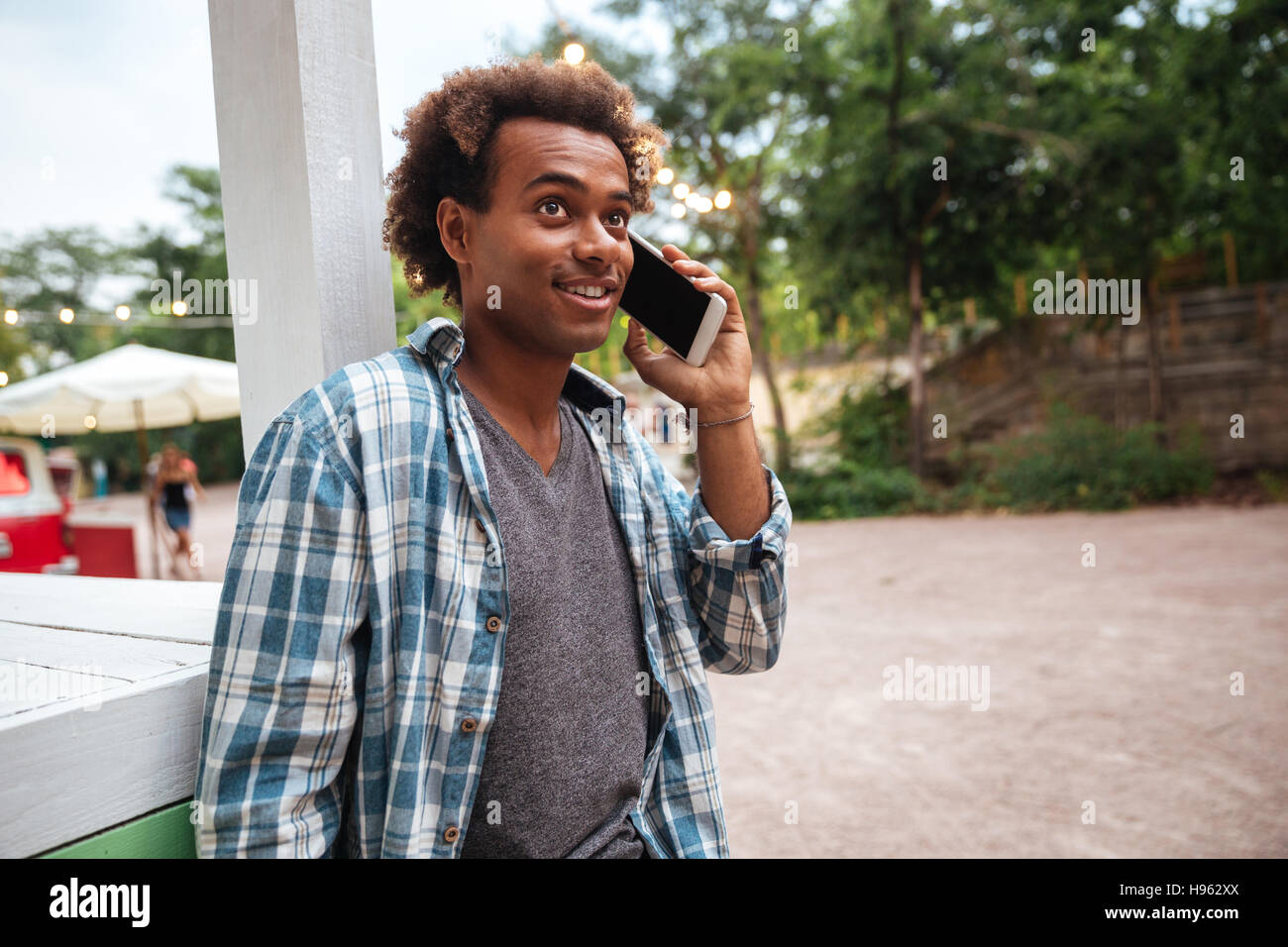 Cheerful african young man talking on cell phone outdoors Stock Photo