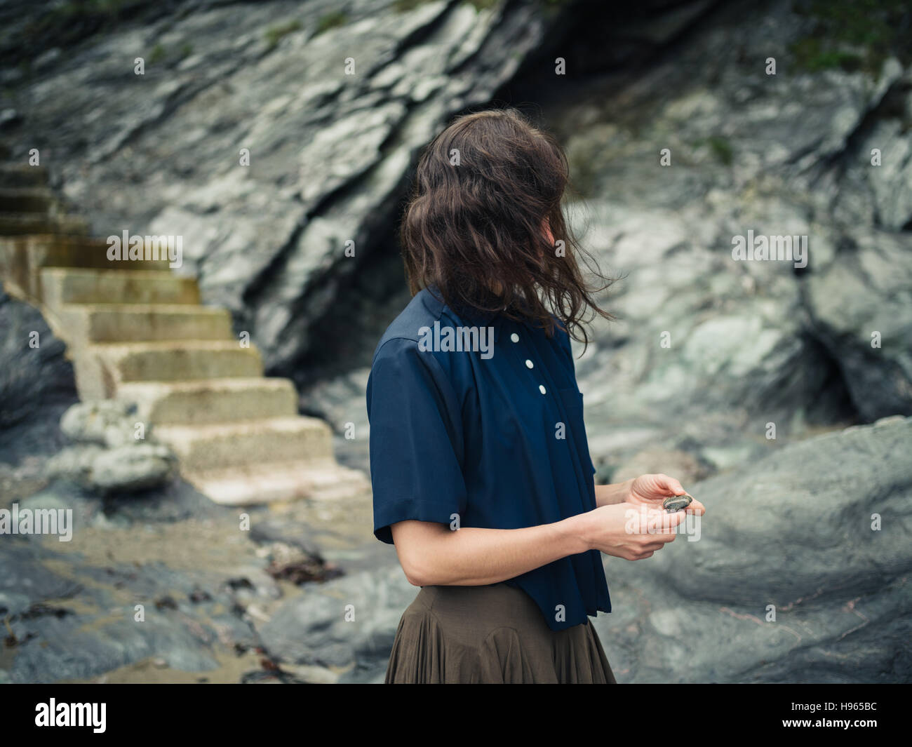 A young woman with the wind blowing in her hair is standing outside in ...