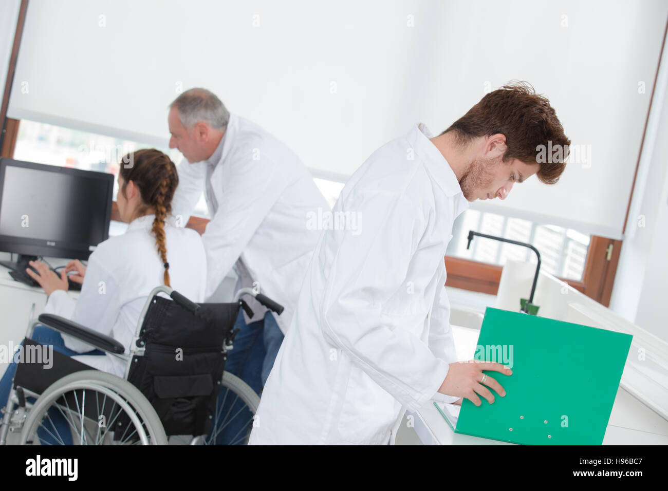 manager assisting wheelchair worker in a lab Stock Photo