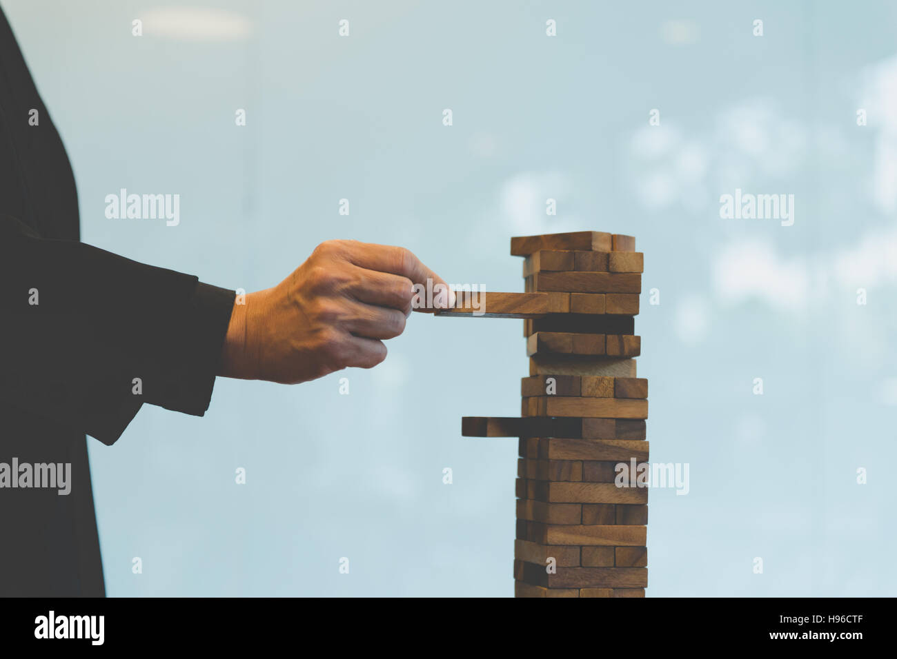 planning, risk and strategy in business, businessman gambling placing wooden block on a tower Stock Photo