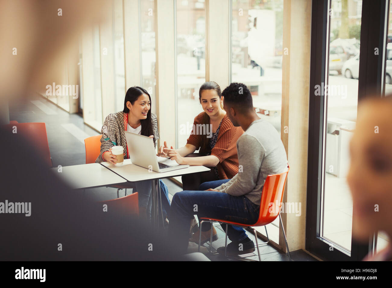 College students using laptop in cafeteria Stock Photo