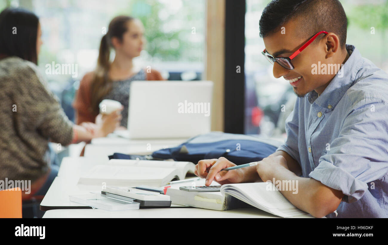 Male college student doing math homework with textbook and calculator Stock Photo