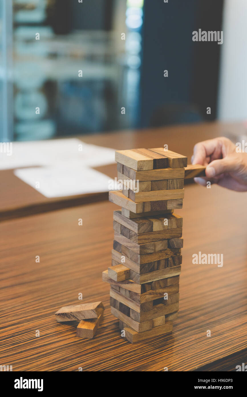 planning, risk and strategy in business, businessman gambling placing wooden block on a tower Stock Photo