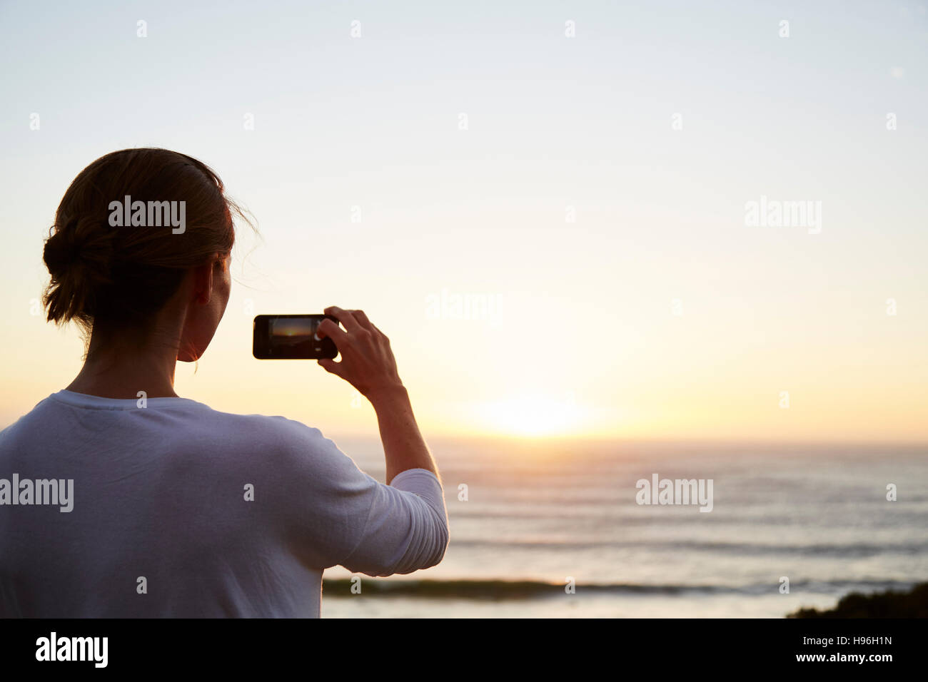 Woman photographing sunset over ocean with camera phone Stock Photo - Alamy