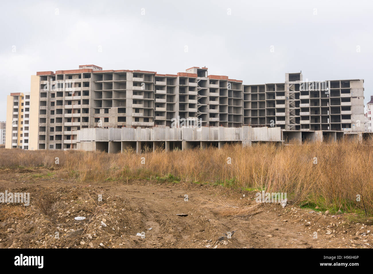 Abandoned construction of multi-storey residential complex, overgrown with weeds Stock Photo