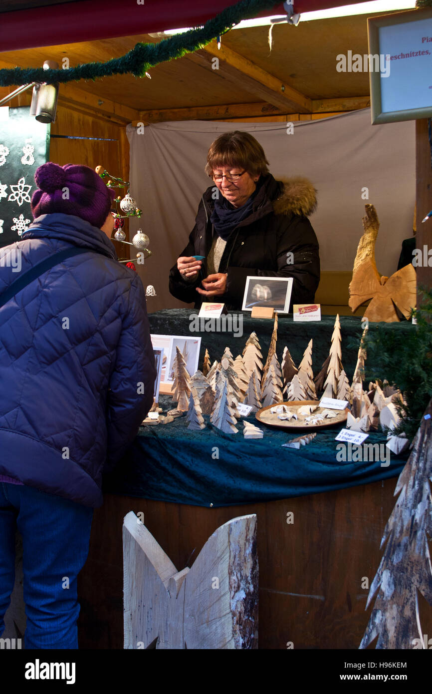 Christmas Market, Hohenzollern Castle, Hechingen Germany, woman at a craft booth discussing  carved wooden figures Stock Photo