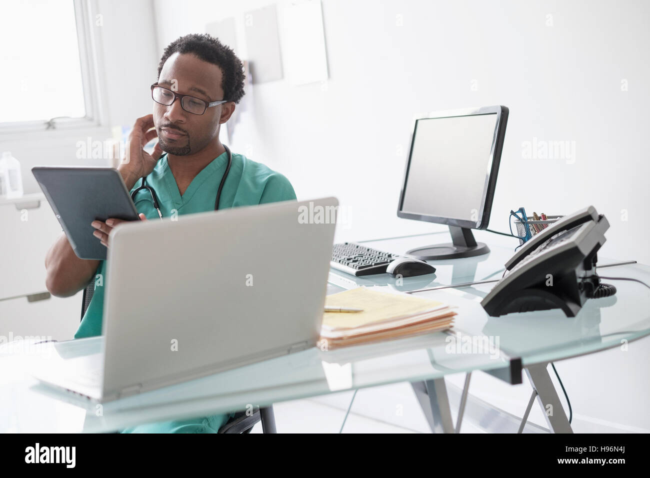 Male doctor working with digital tablet at desk Stock Photo
