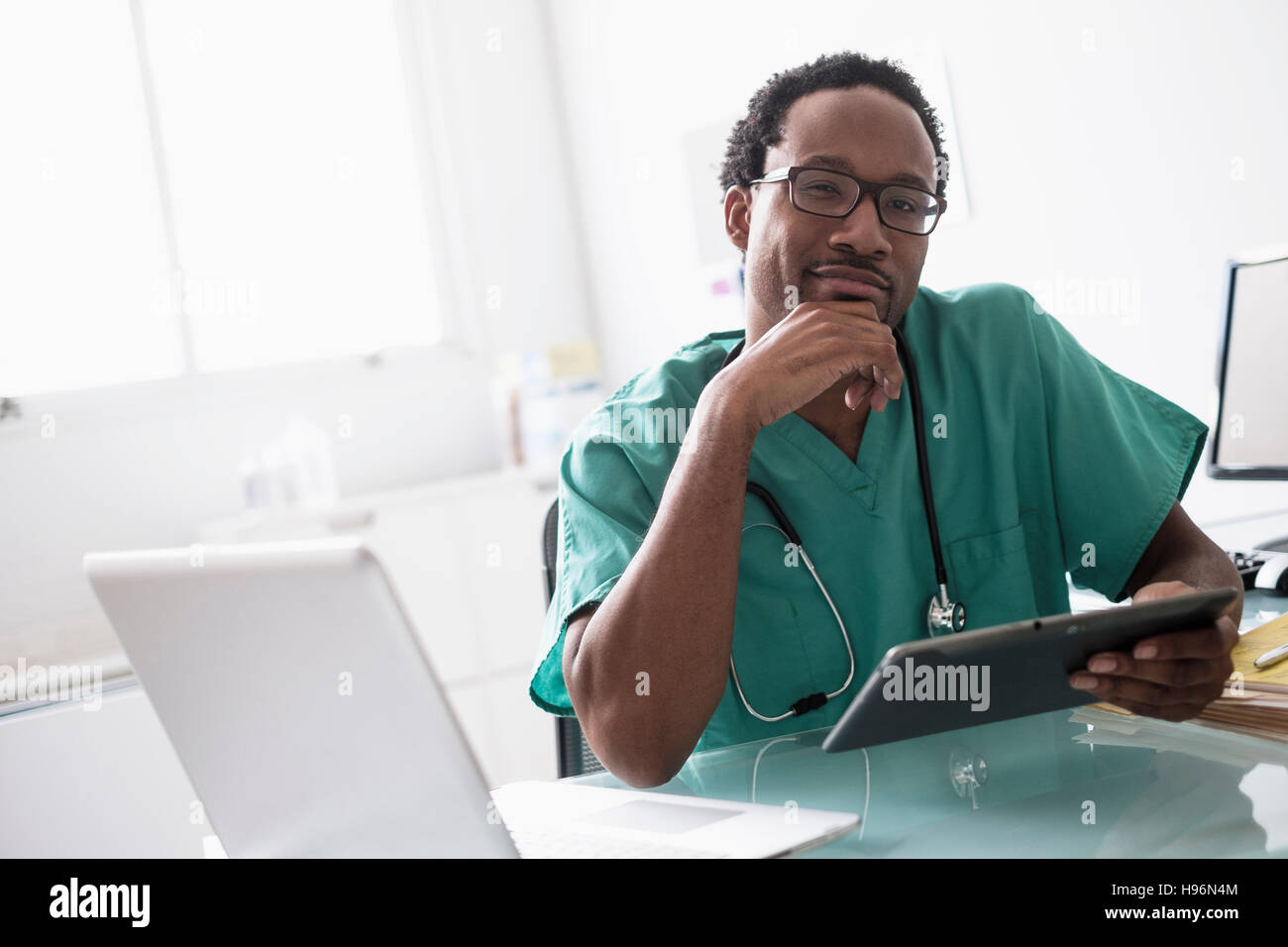 Male doctor working with digital tablet at desk Stock Photo
