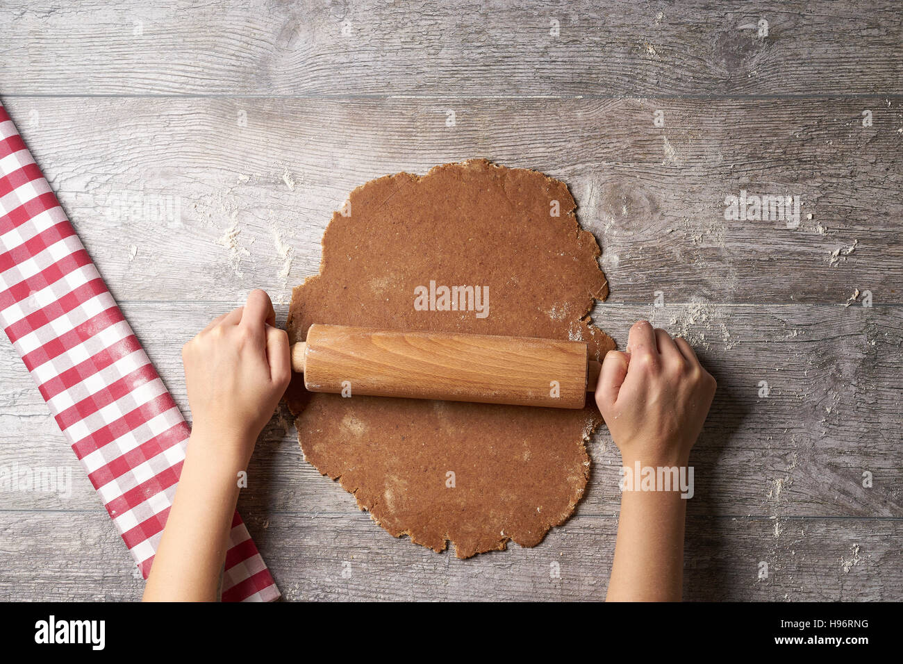 Hands rolling out Cookie dough on table from above Stock Photo