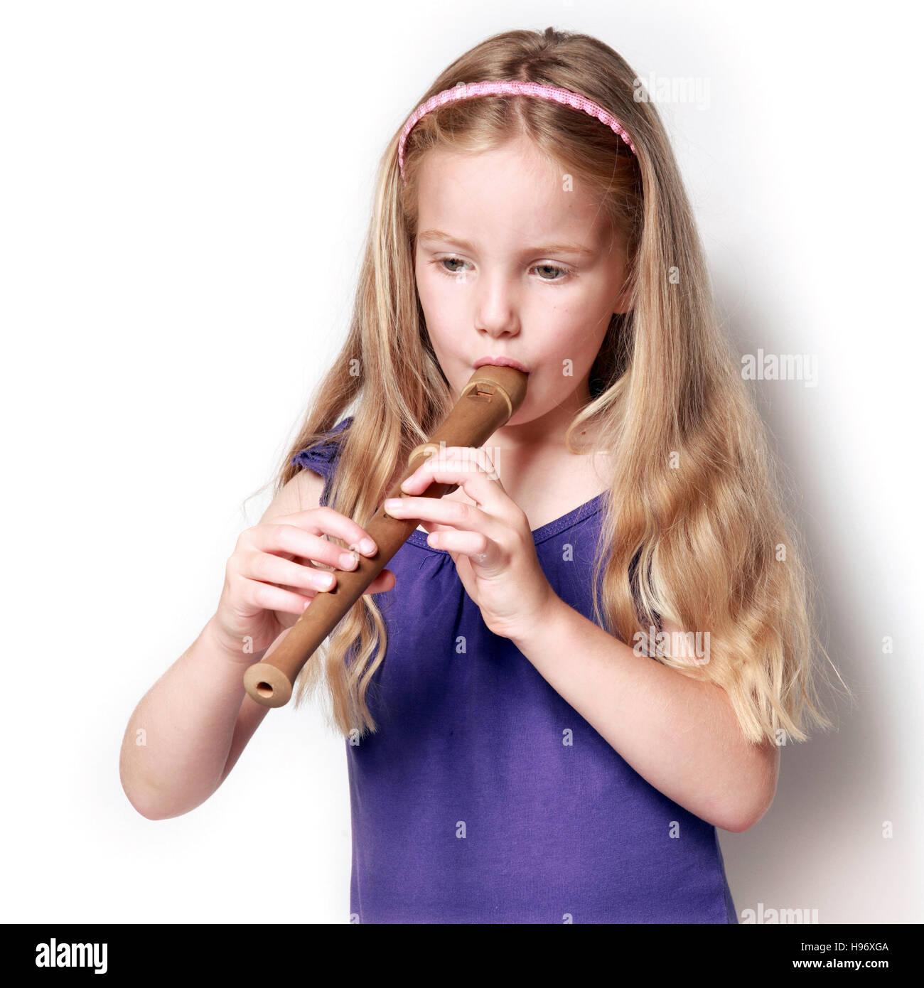 square picture of little girl in purple dress playing the recorder against white background Stock Photo