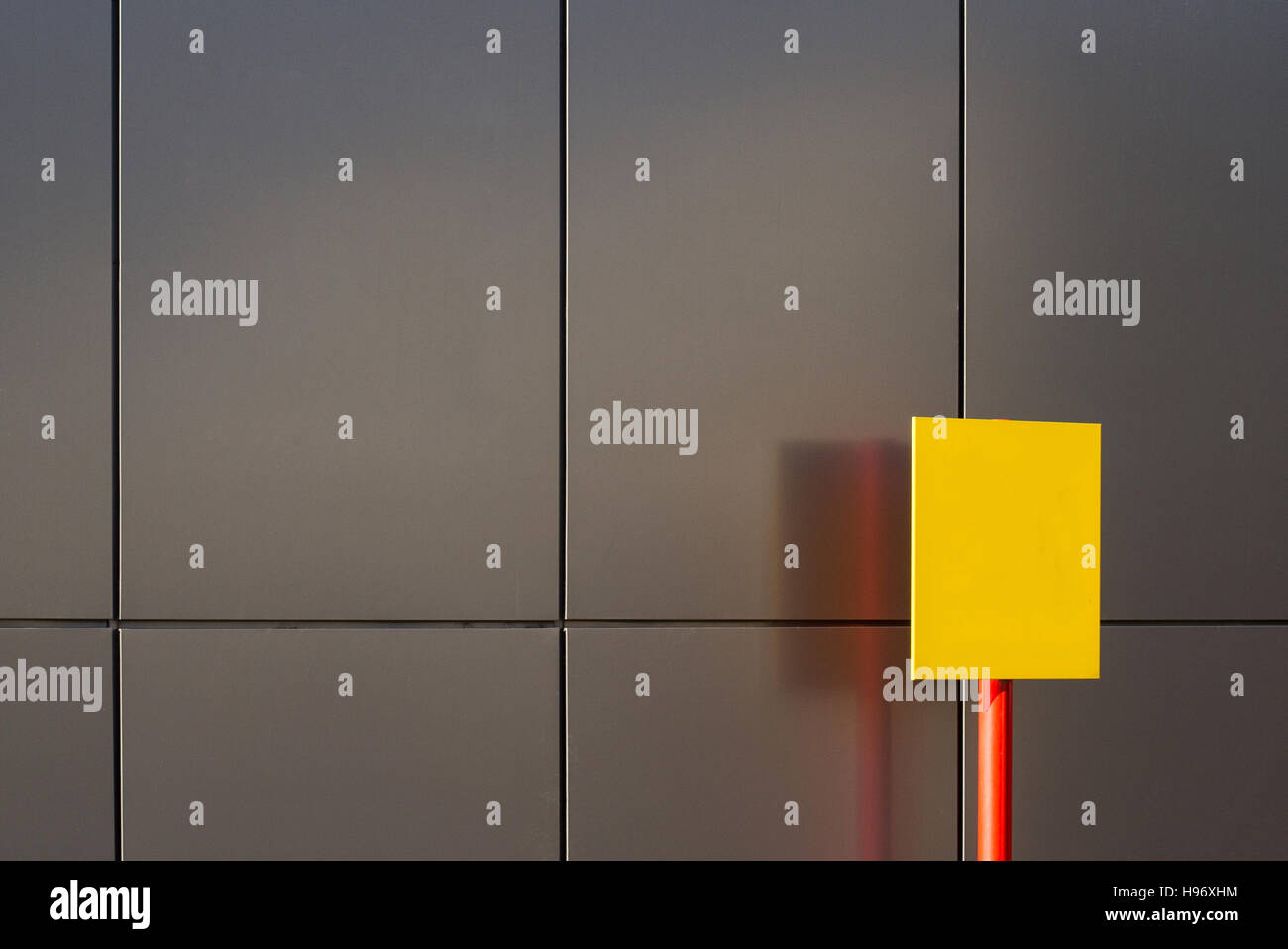 detail of city building with grey metallic texture with yellow sign in front Stock Photo