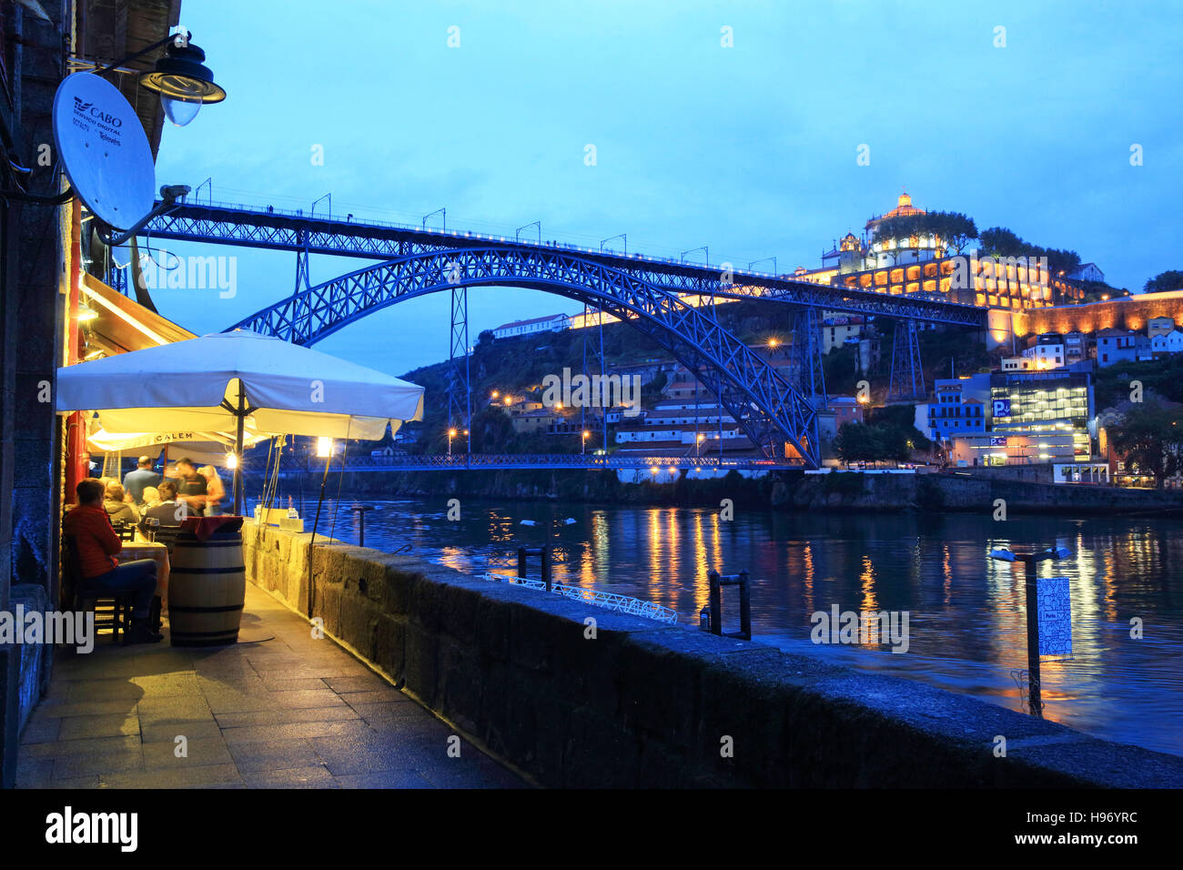 A restaurant on the waterfront of the River Douro, at dusk, with the Dom Luis 1 bridge behind, in Porto, north Portugal, Europe Stock Photo